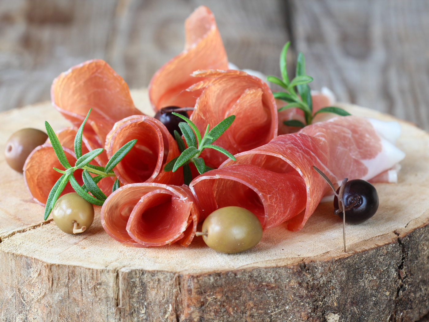 Прошутто  с оливками на деревянном столе 