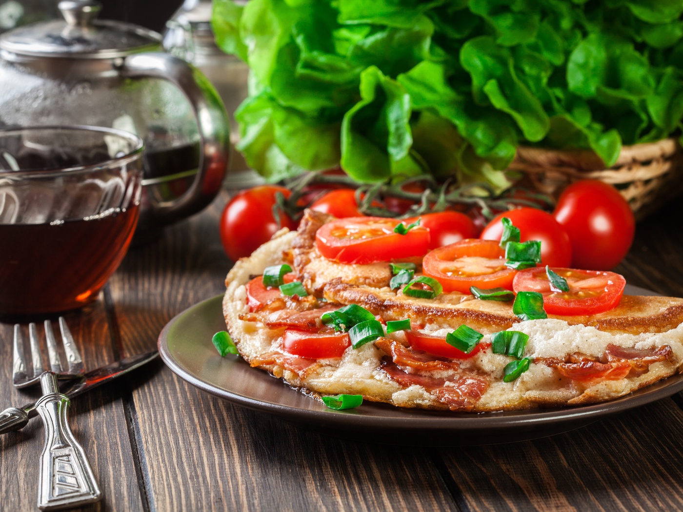 Пицца с помидорами на столе с чаем и зеленью 