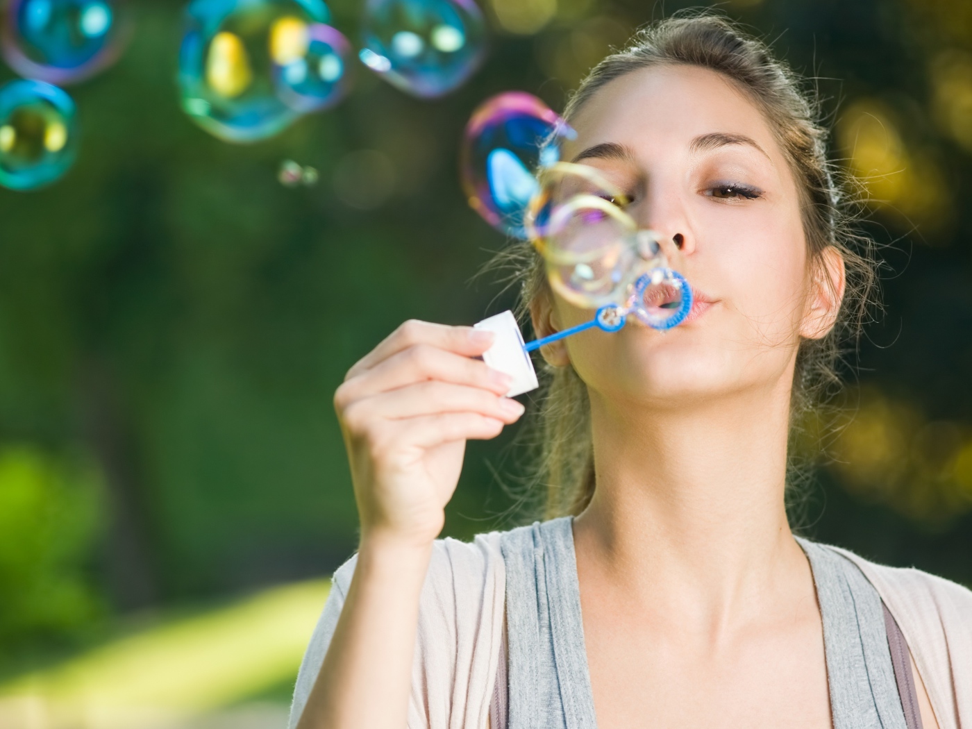 Милая молодая девушка пускает мыльные пузыри