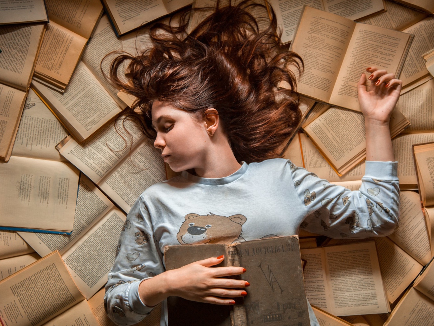 Молодая девушка спит на книгах