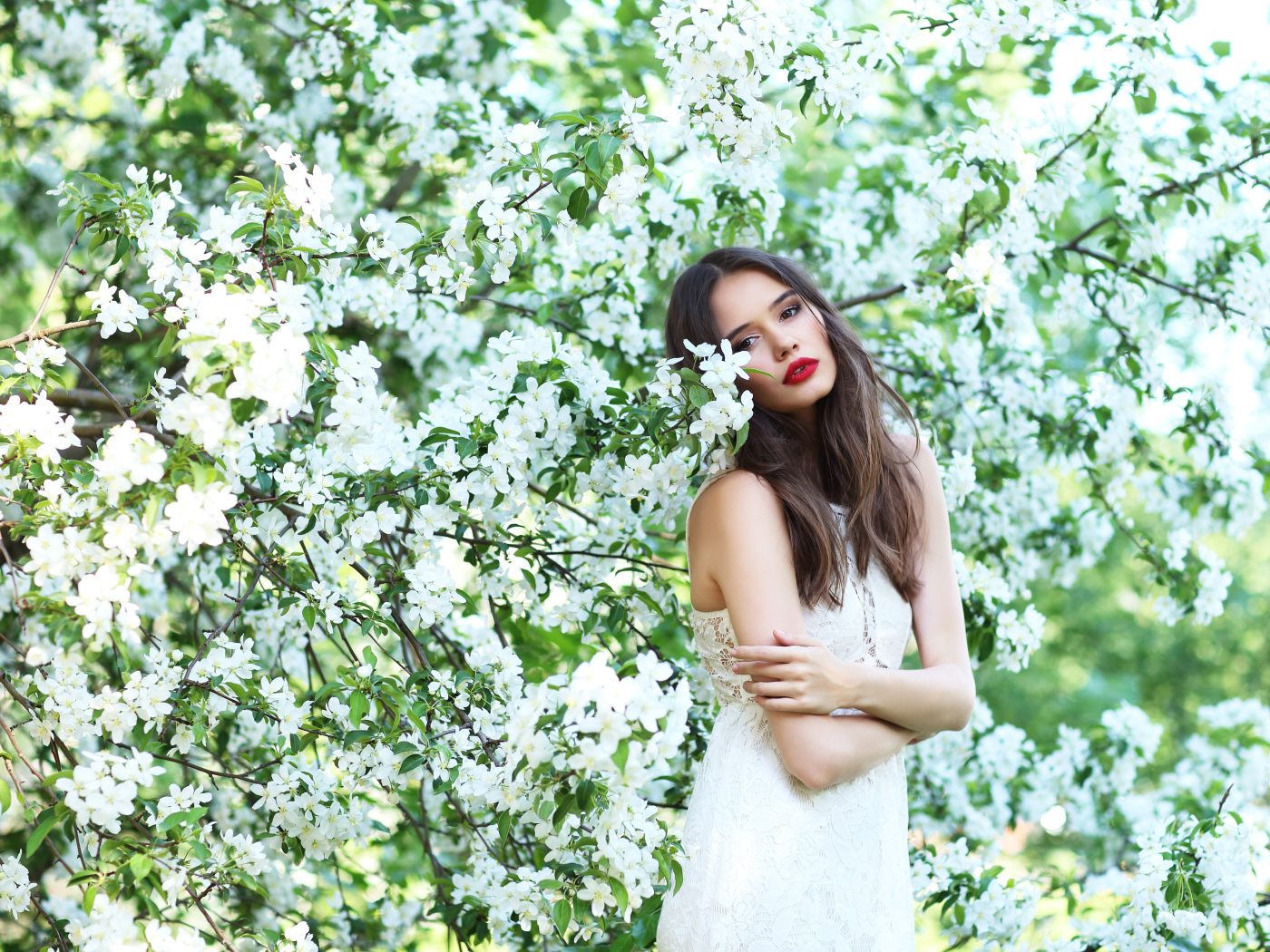 Красивая шатенка в цветущих ветках яблони