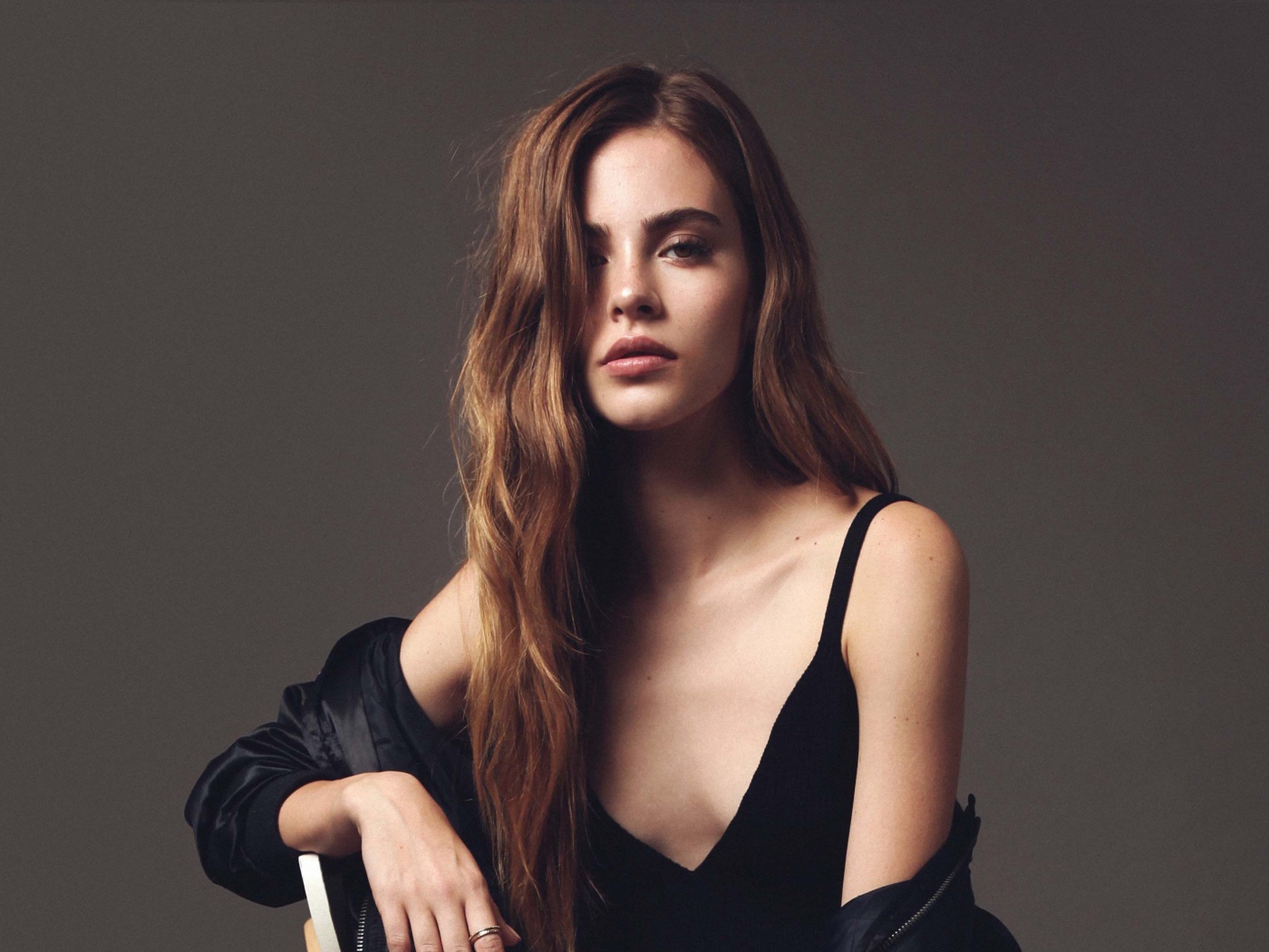 Красивая брюнетка в черном платье сидит на стуле