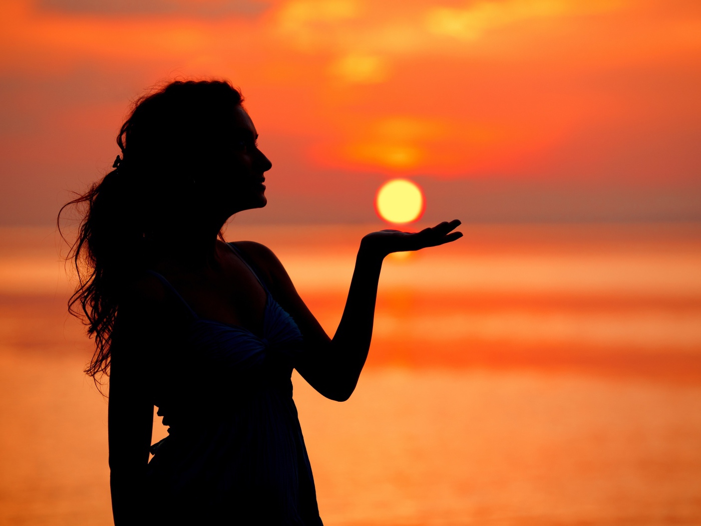 Красивая девушка держит солнце в ладони на закате