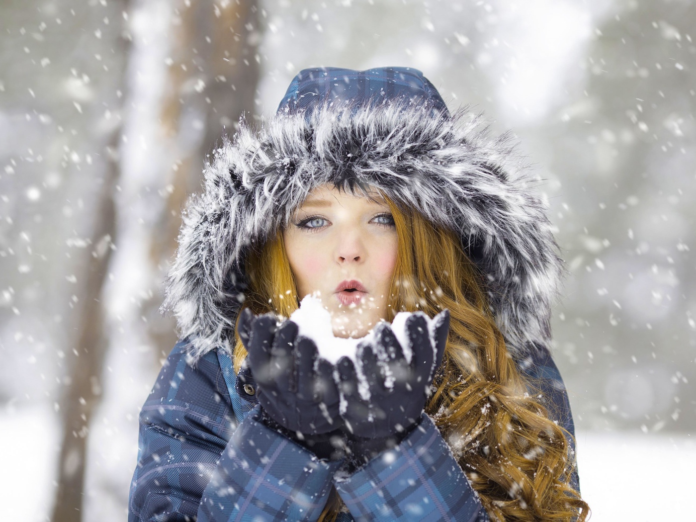 Красивая девушка в теплой куртке со снегом в руках