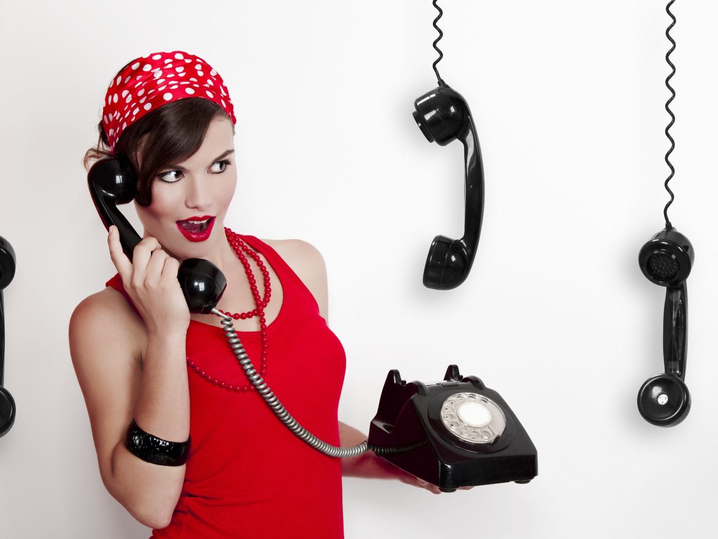 Красивая девушка в красном с черным старым телефоном в руках