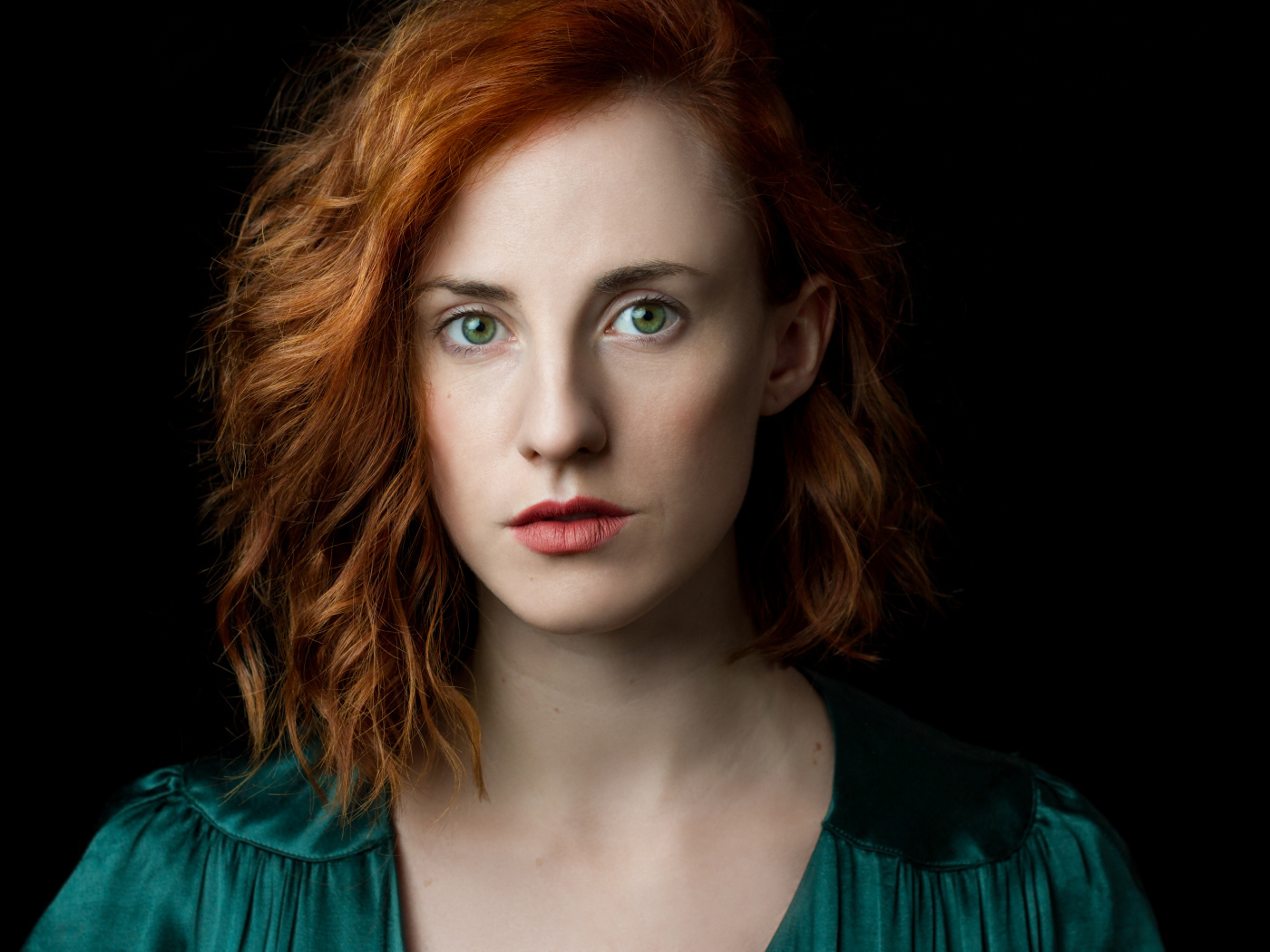 Красивая зеленоглазая рыжеволосая девушка на черном фоне 