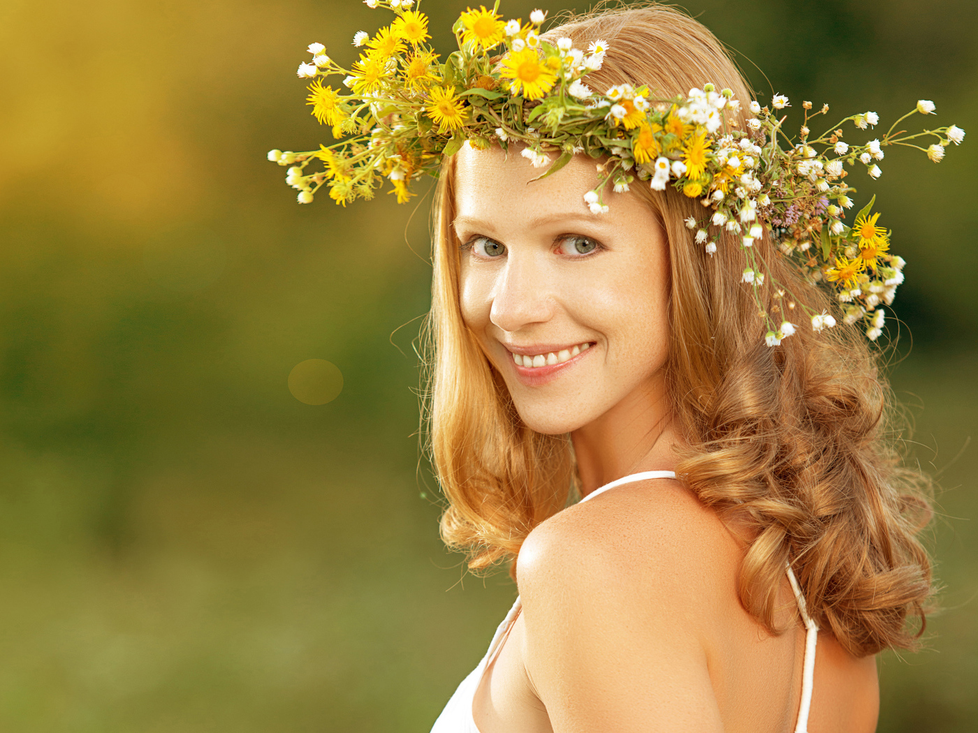Красивая улыбающаяся девушка с венком из полевых цветов на голове