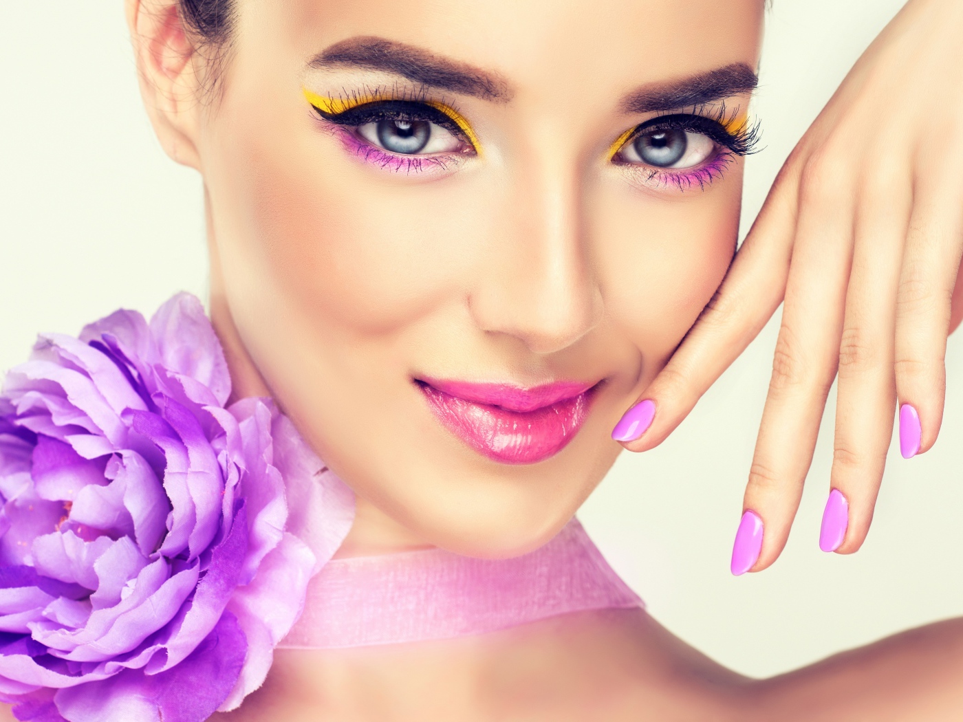 Красивая молодая девушка с ярким макияжем и сиреневым цветком на шее