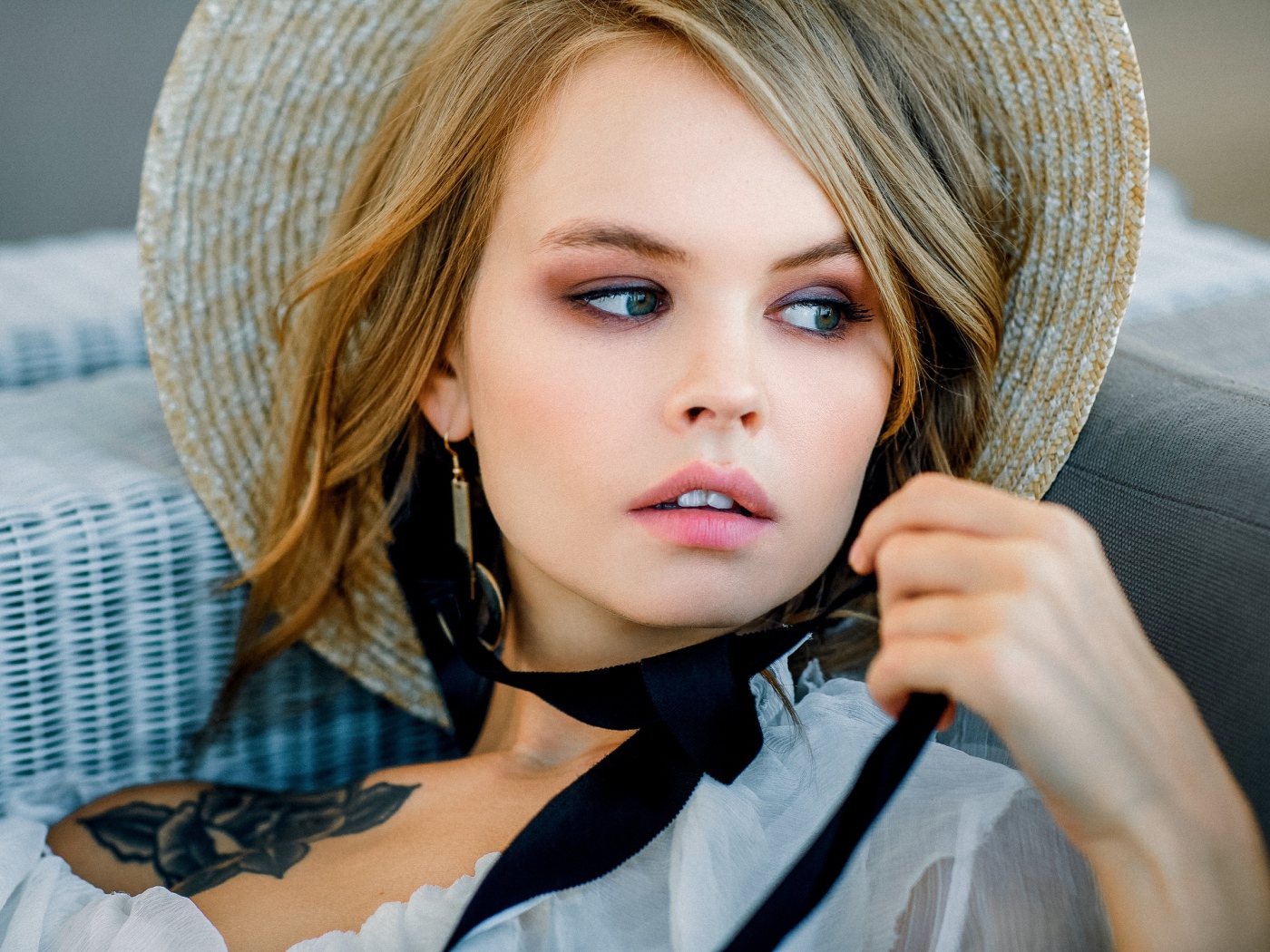 Грустная блондинка в шляпе с татуировкой