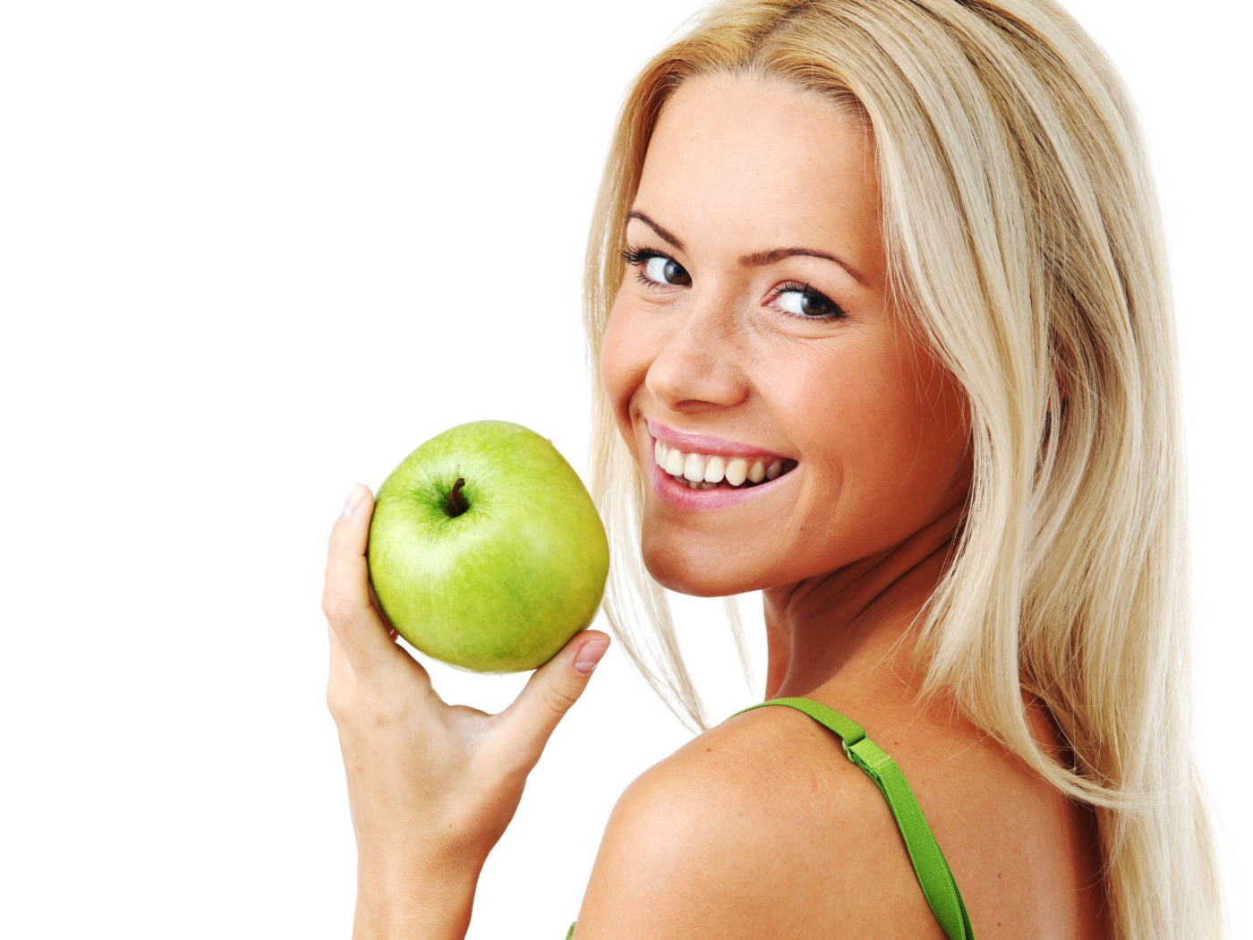 Улыбающаяся девушка блондинка с зеленым яблоком в руке на белом фоне