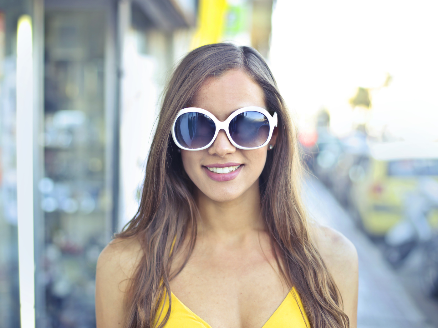 Улыбающаяся молодая девушка в солнечных очках 