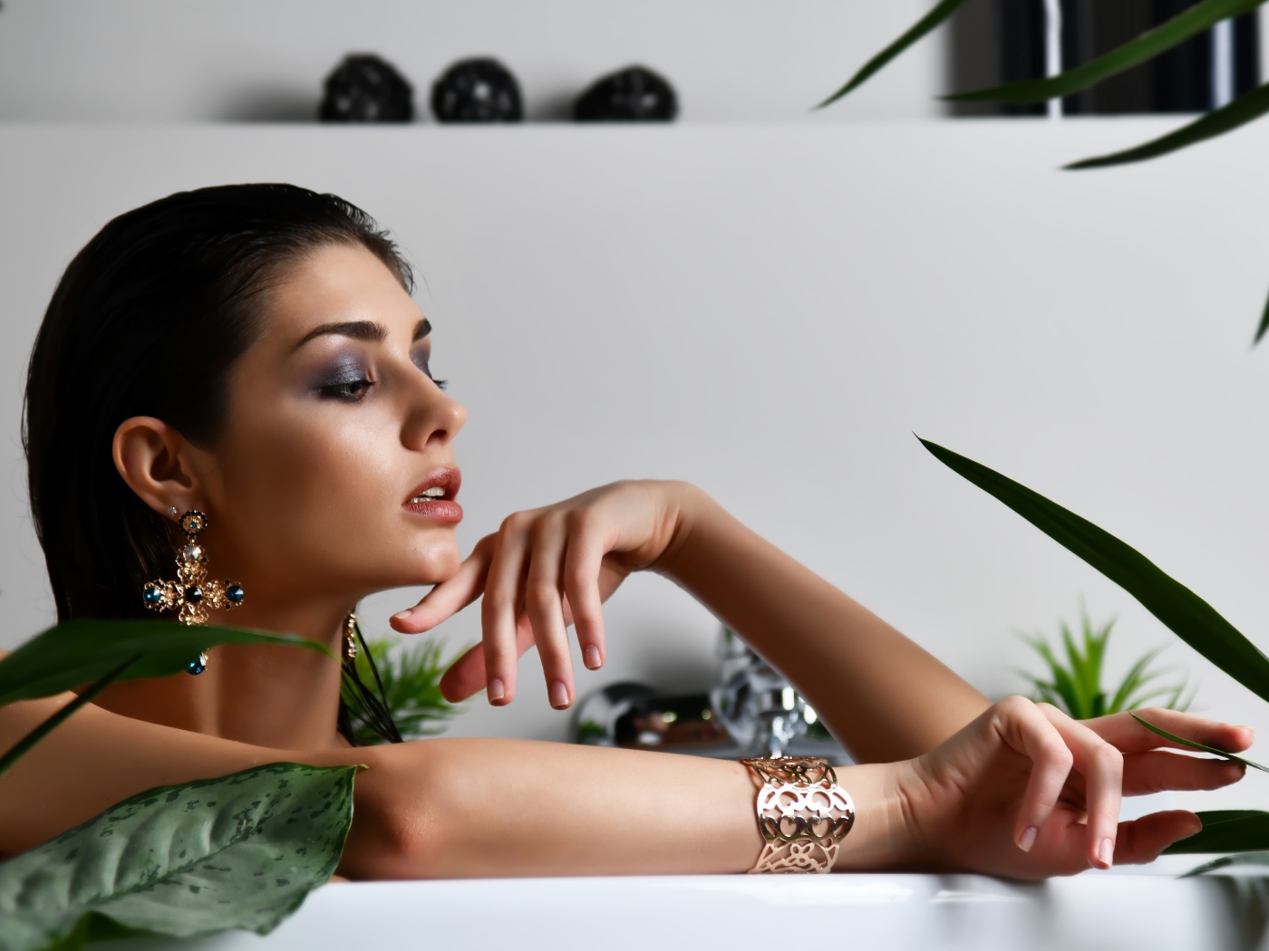 Девушка в дорогих украшения лежит в ванной