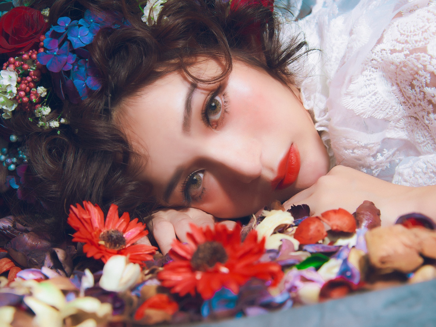 Молодая красивая девушка лежит цветами в волосах