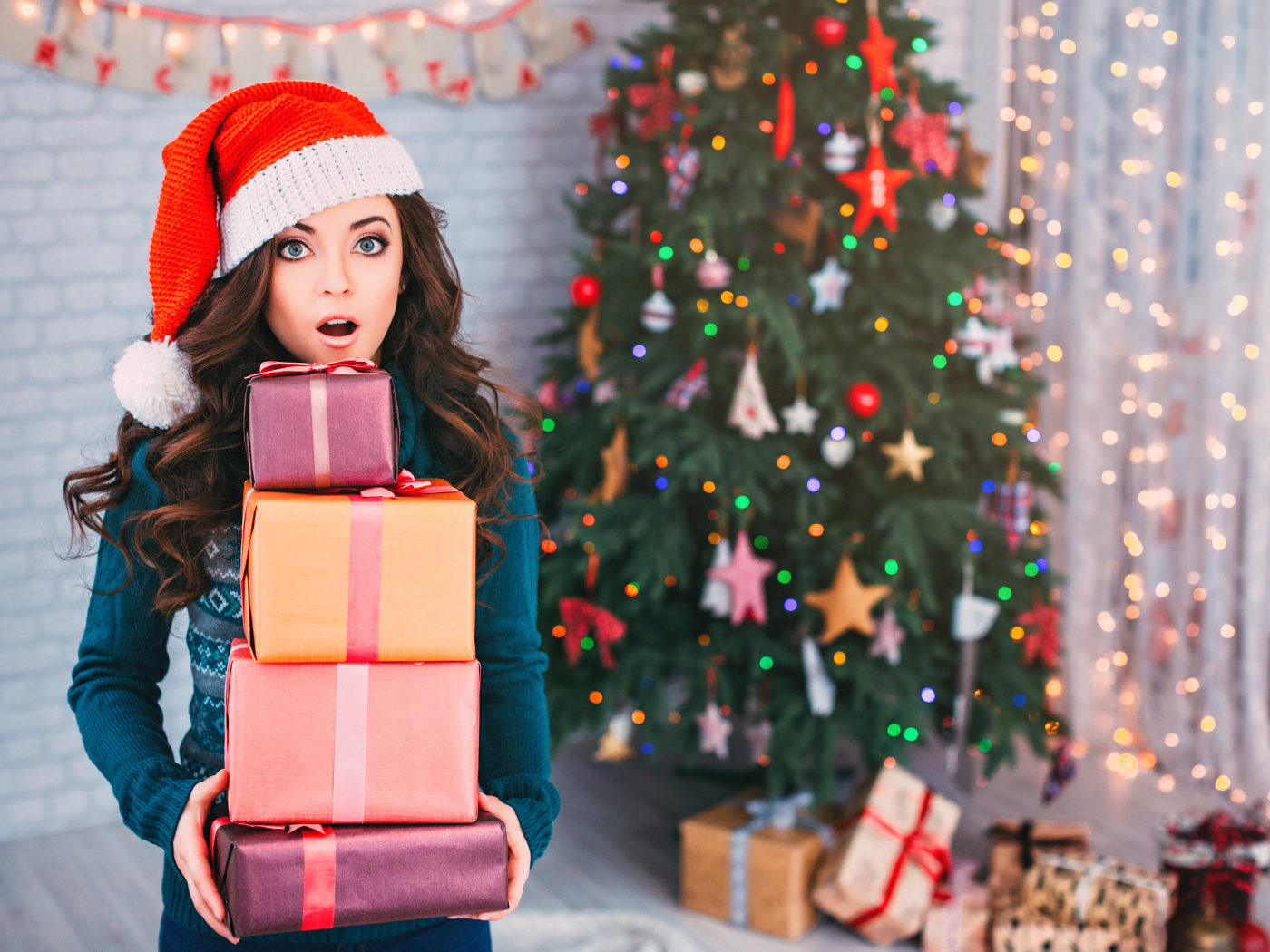 Удивленная девушка с подарками у новогодней елки 