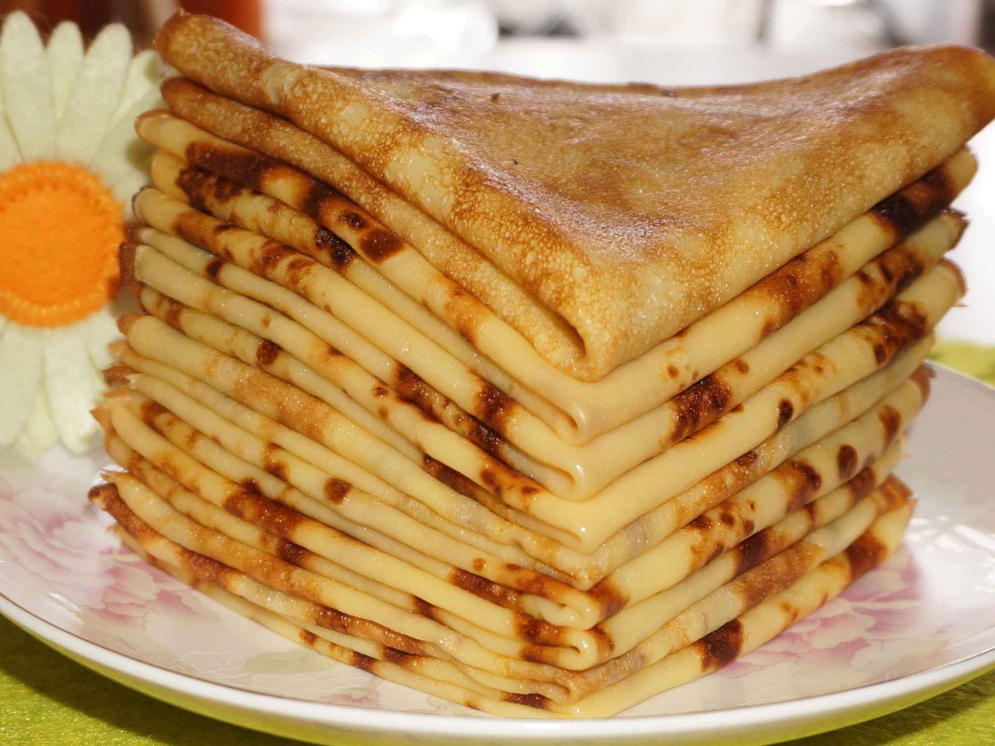 Стопка тонких блинов с ромашкой на Масленицу