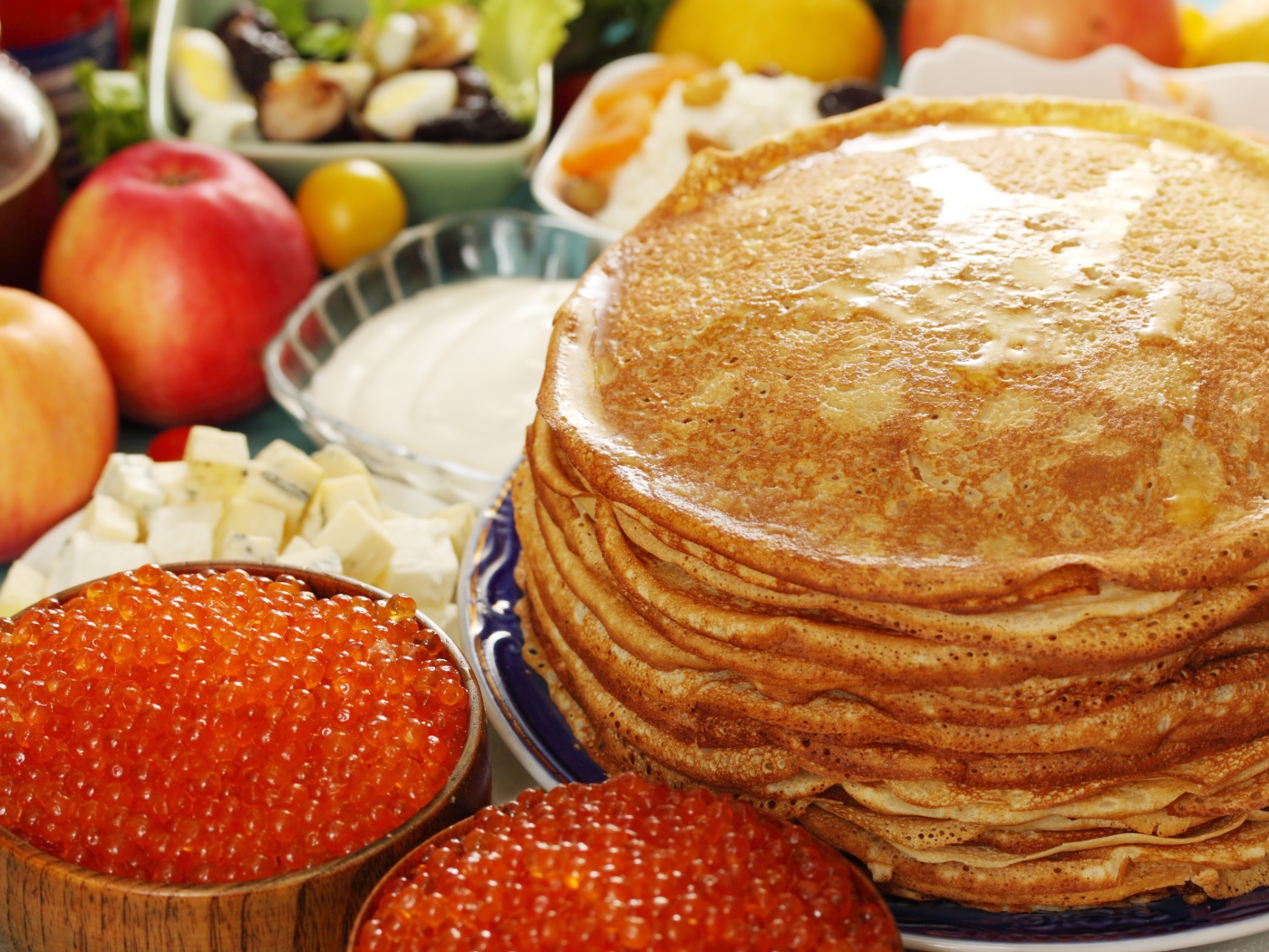 Румяные тонкие блины на столе с красной икрой на Масленицу