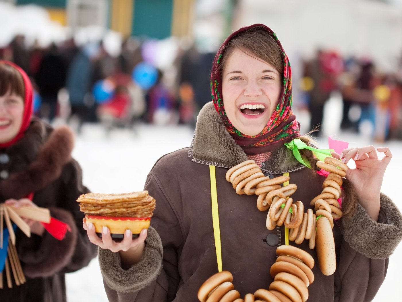 Улыбающаяся девушка с угощениями на праздник Масленица 2018