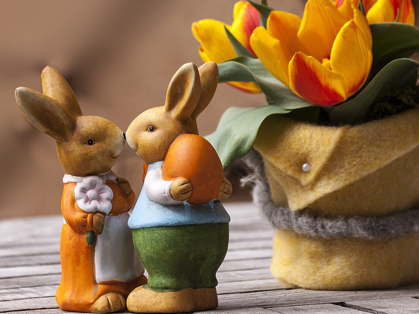 Статуэтки пасхальных кроликов на столе с тюльпанами