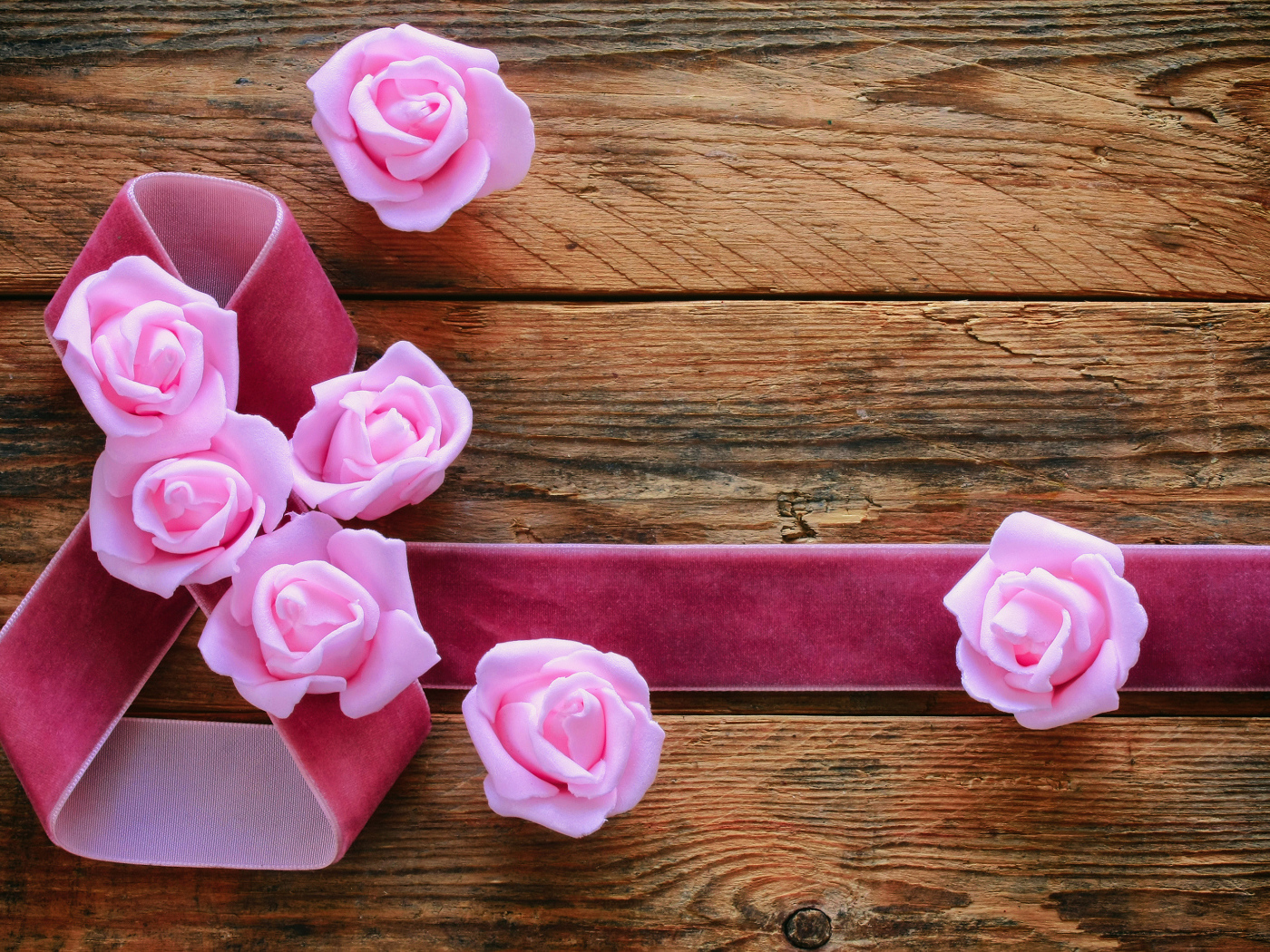 Восьмерка из ленты с розовыми розами на деревянном фоне на Международный женский день