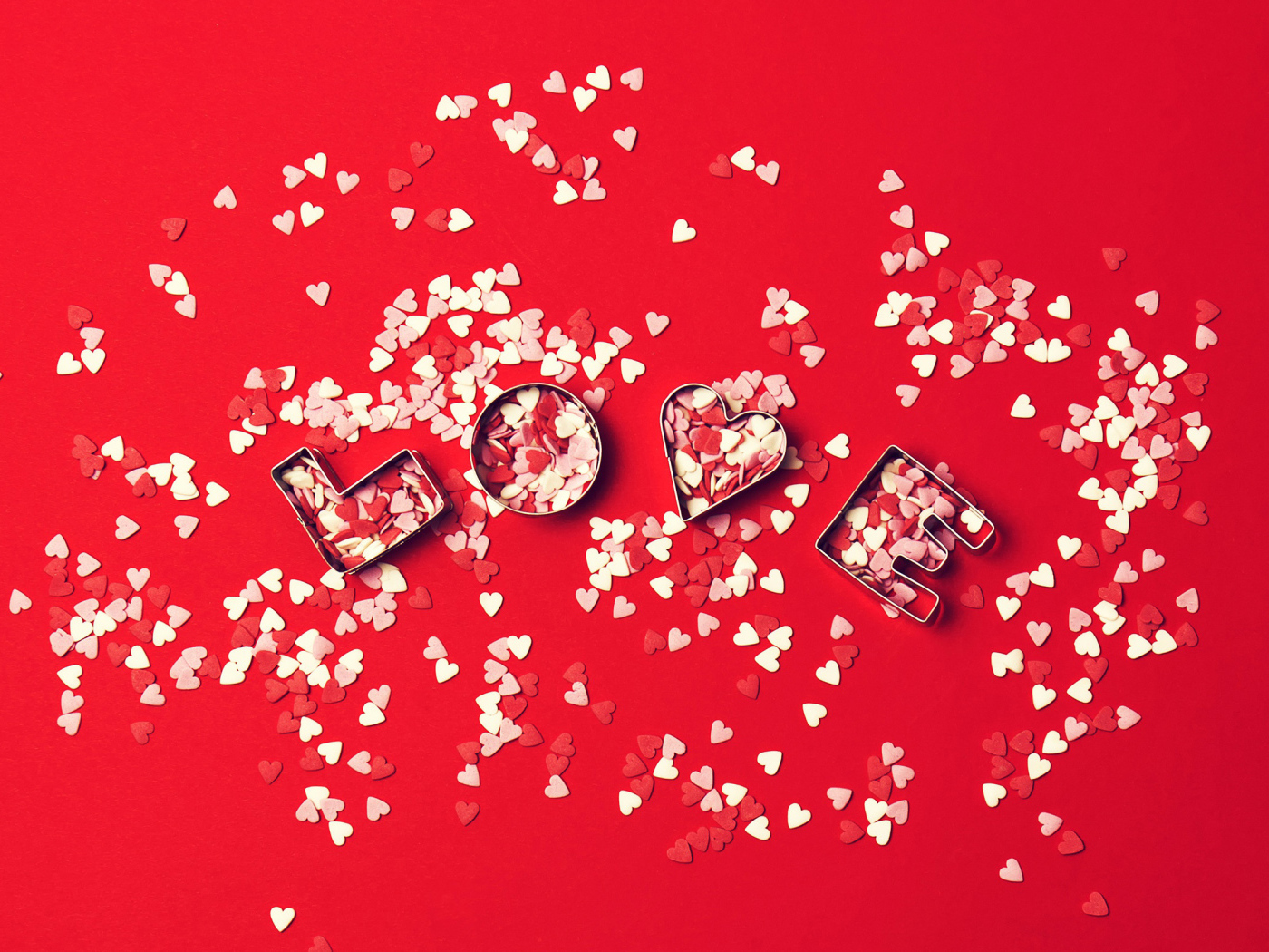 Надпись любовь из маленьких  сердечек на красном фоне