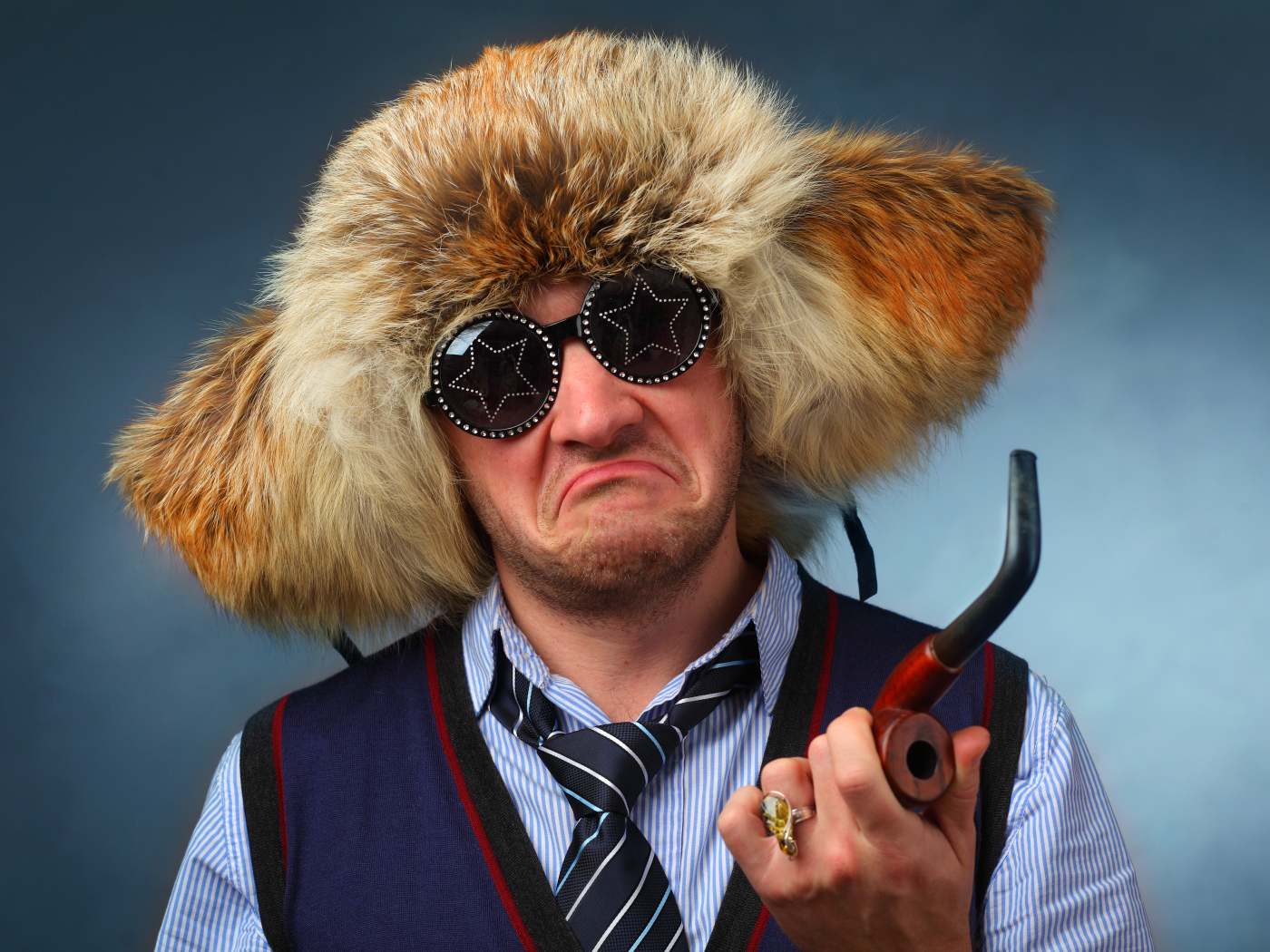 Мужчина в меховой шапке в модных очках с трубкой в руке