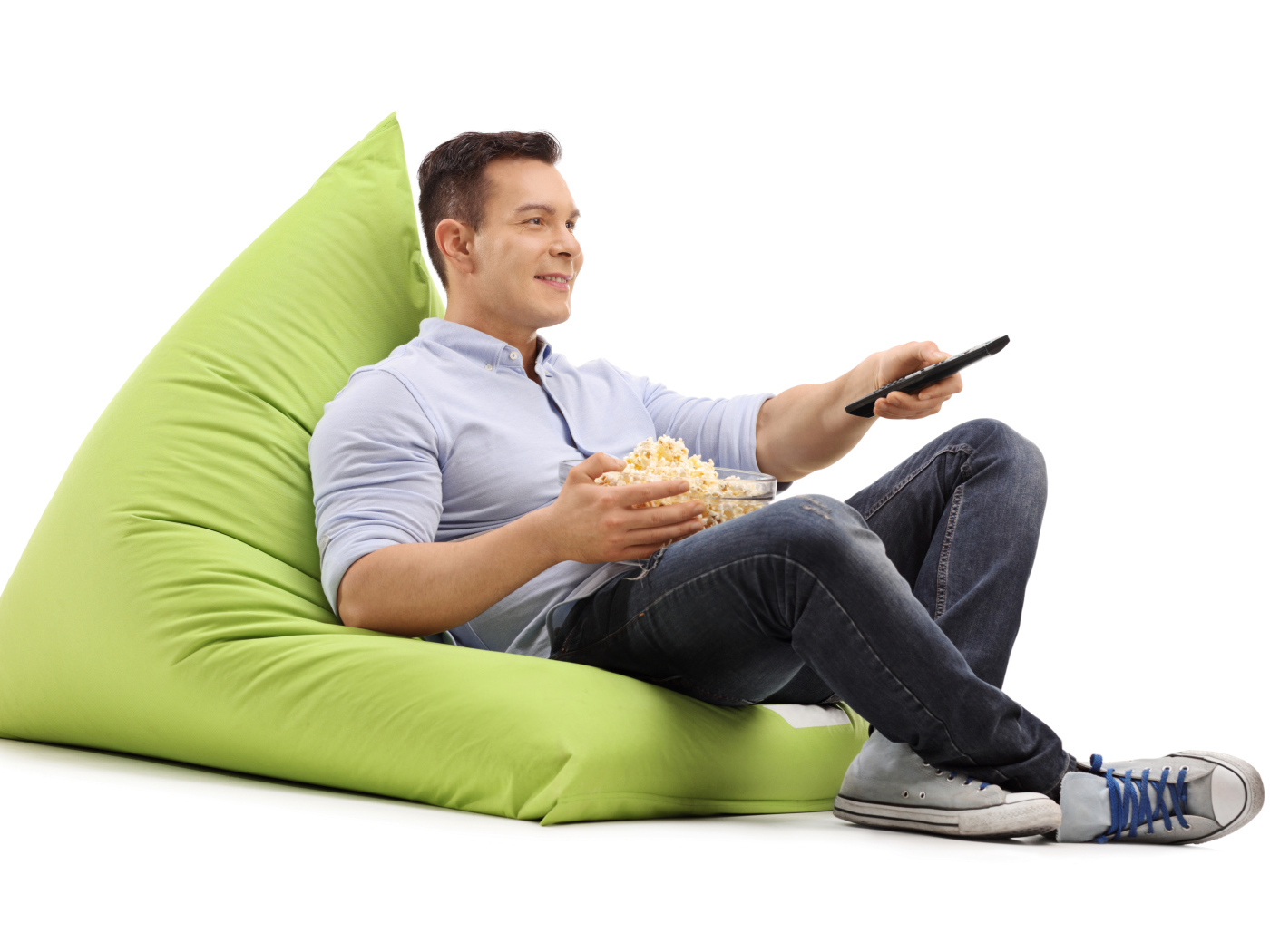 Мужчина с попкорном и пультом от телевизора лежит на зеленой подушке