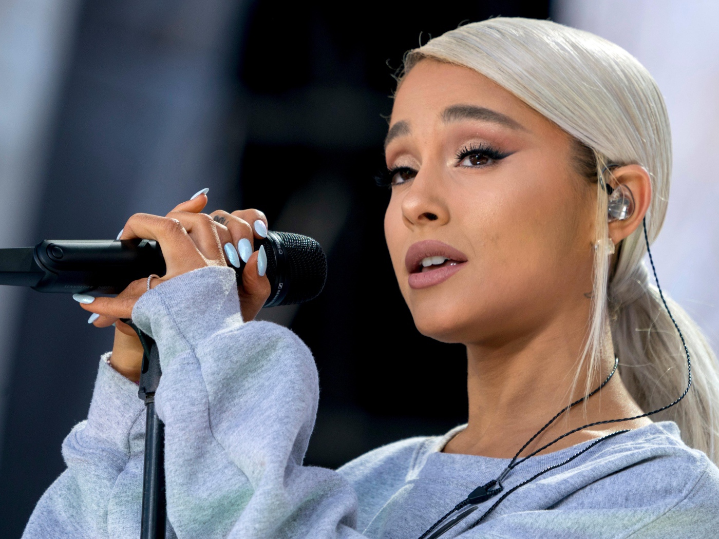 Светловолосая певица Ариана Гранде с микрофоном на сцене 