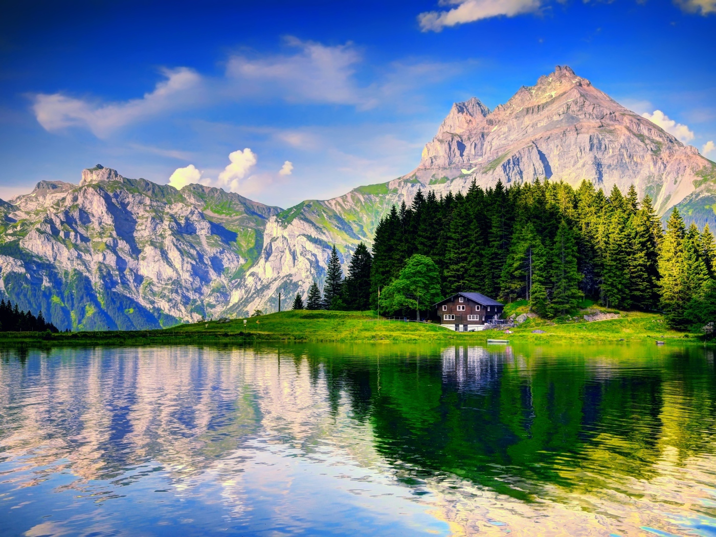 Лес и горы отражаются в озере под красивым голубым небом с белыми облаками