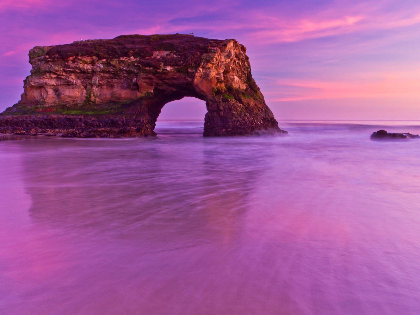 Гора с аркой в океане на фоне красивого неба