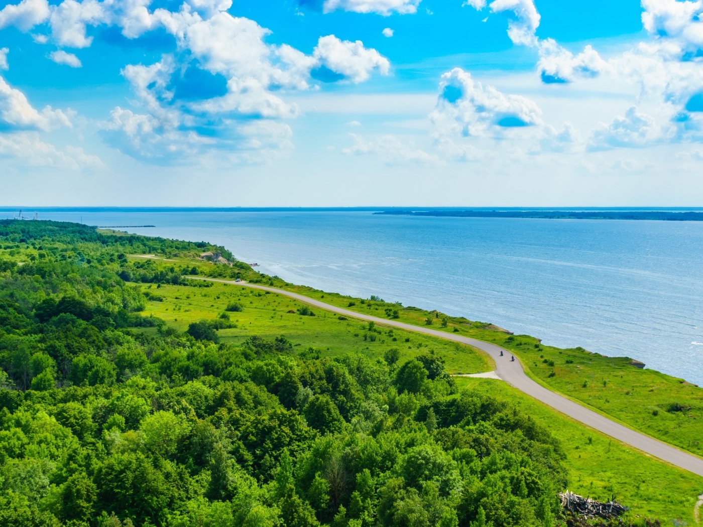 Дорога через побережье вдоль моря под голубым небом с белыми облаками