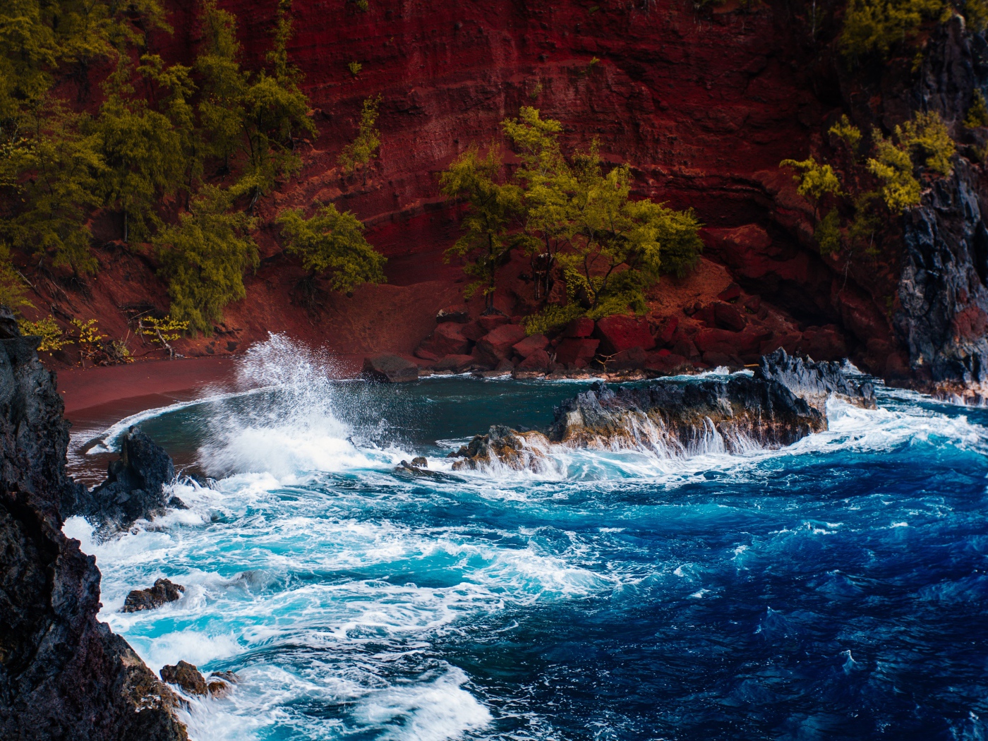 Грубое море брызгает камнями перед красным песчаным океанским заливом в Хане