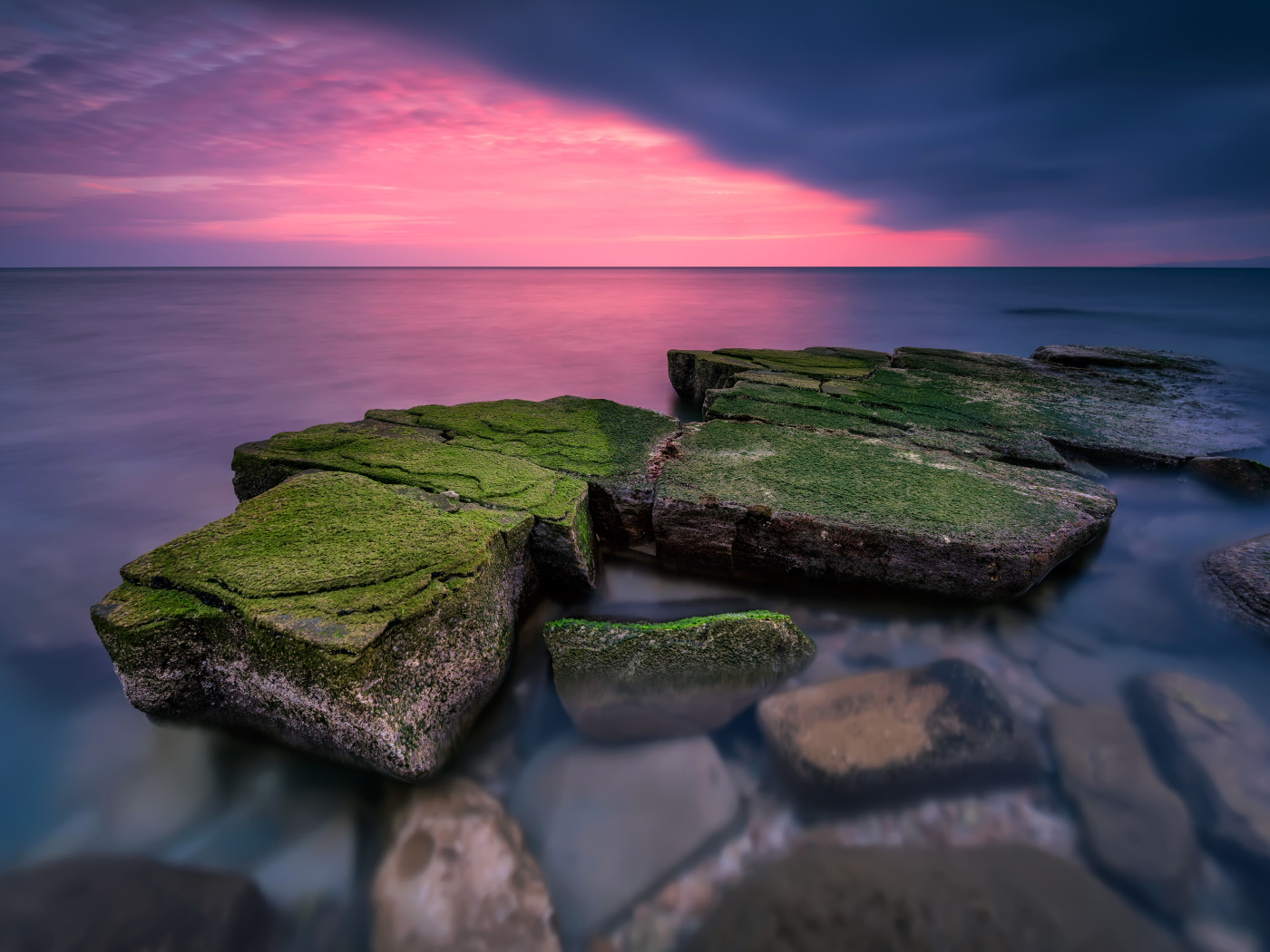 Покрытые зеленым мхом камни в воде