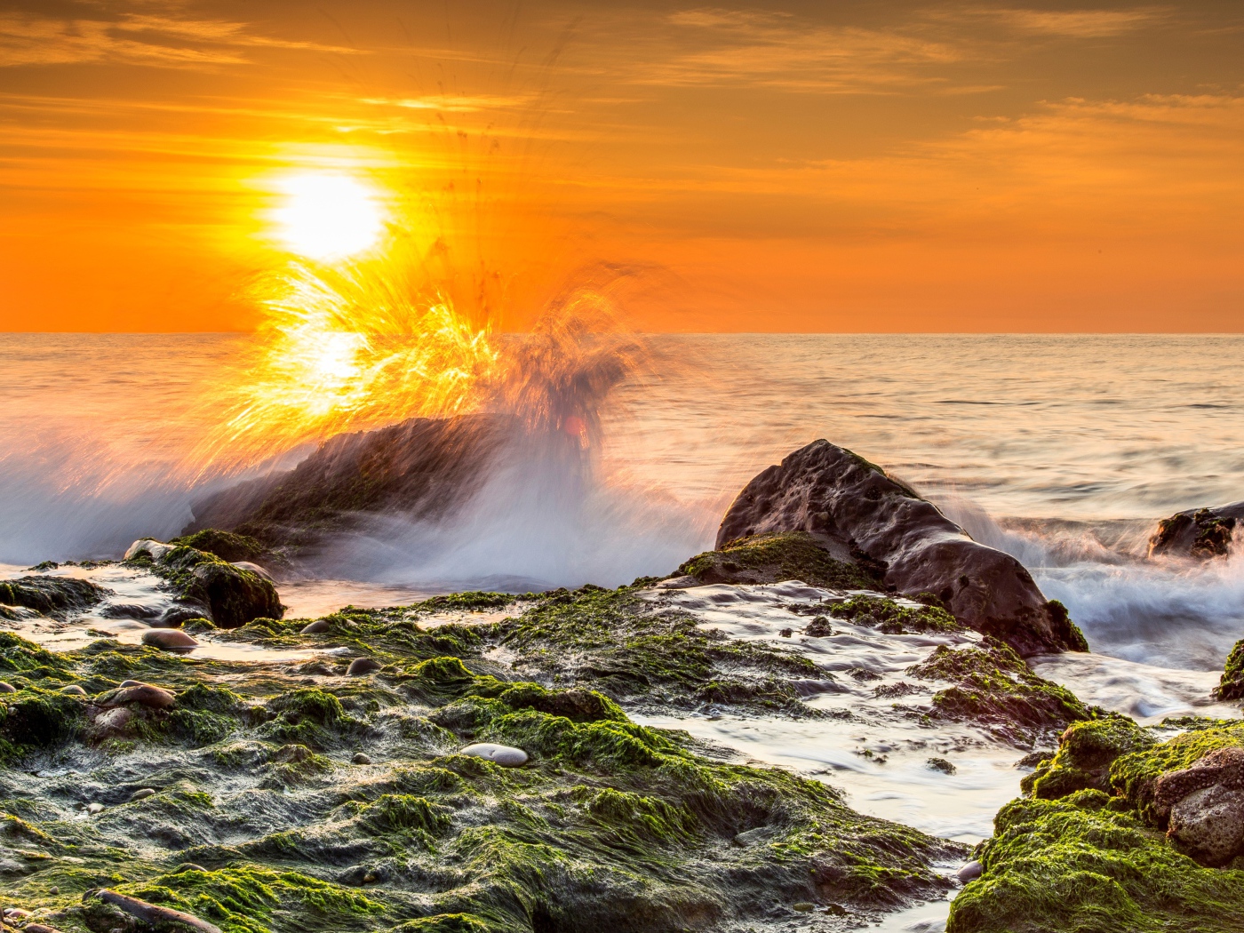 Бушующие волны в море бьются об камни на закате