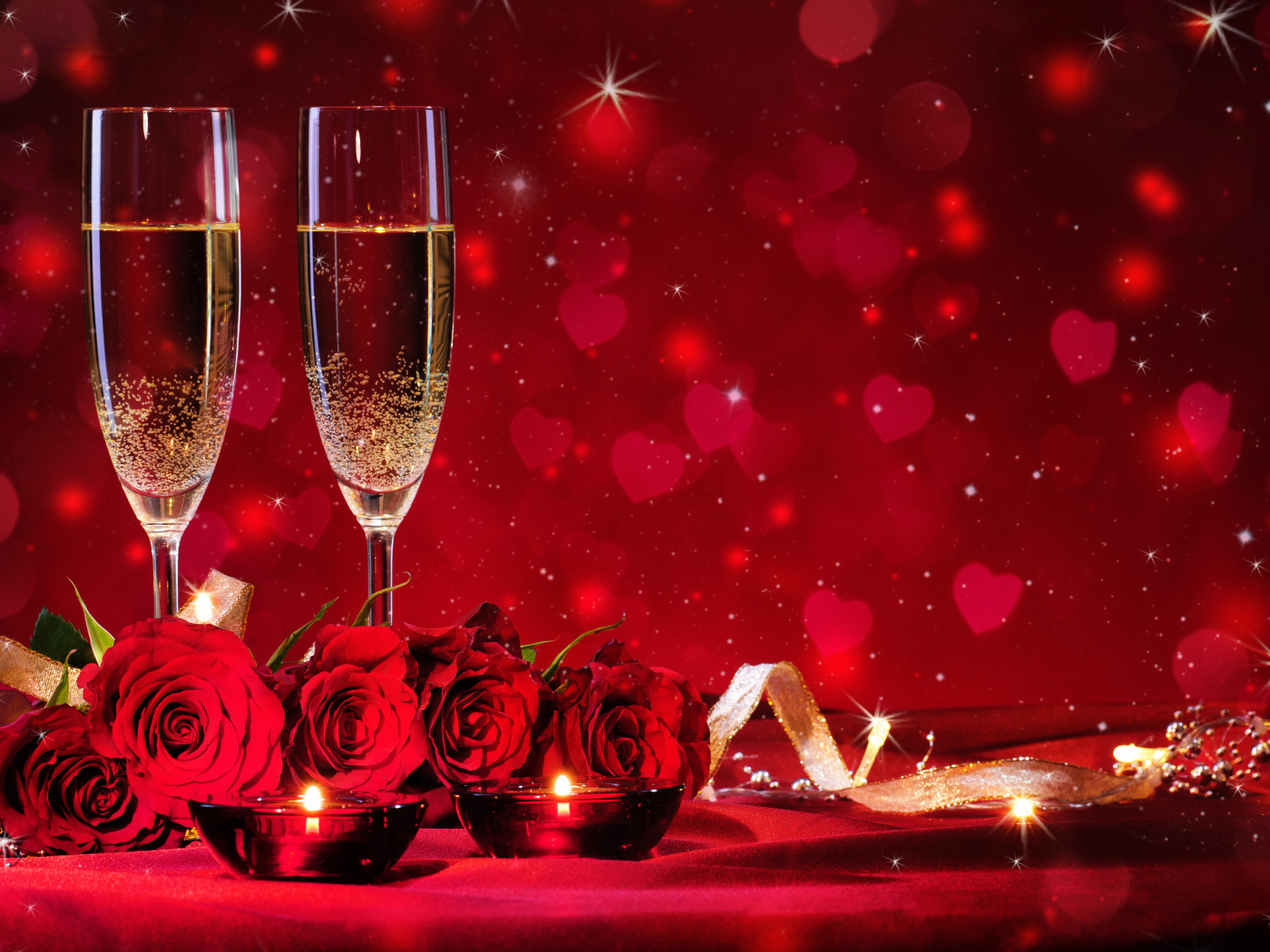 Букет роз и два фужера шампанского с зажженными свечами на красном фоне
