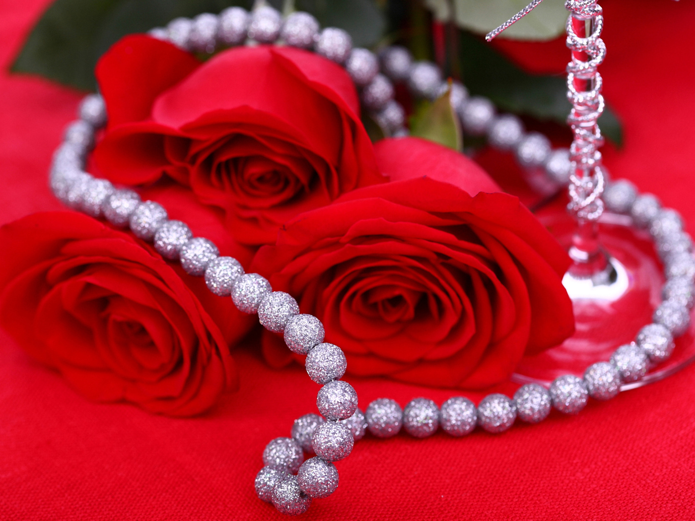 Три красные розы с украшением на красном фоне