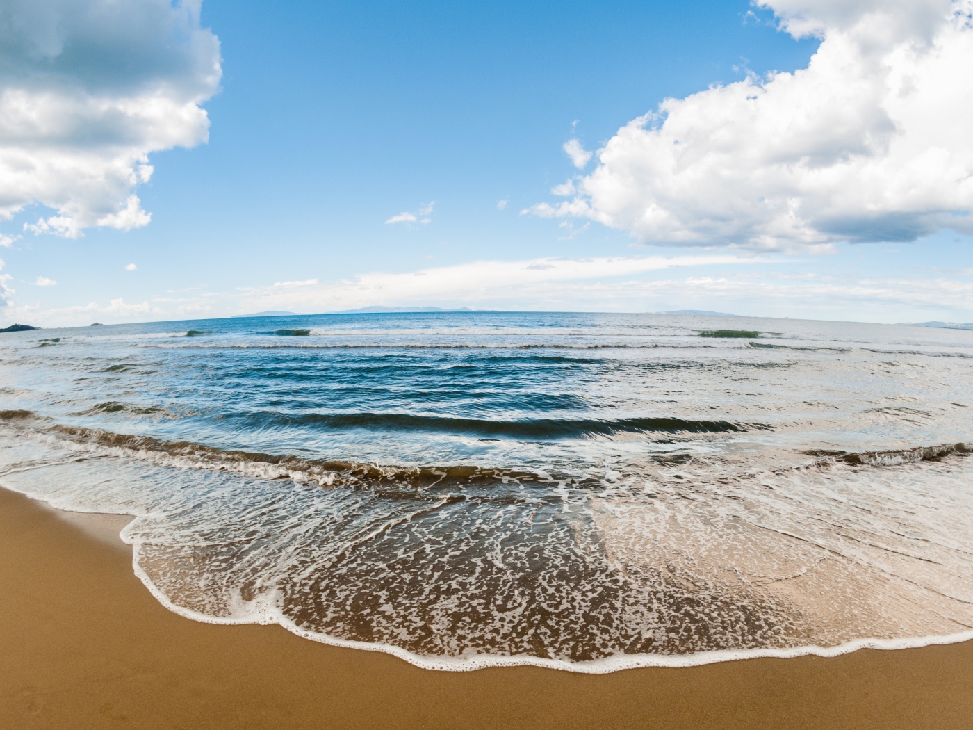 Морская волна на песке под красивым небом с белыми облаками