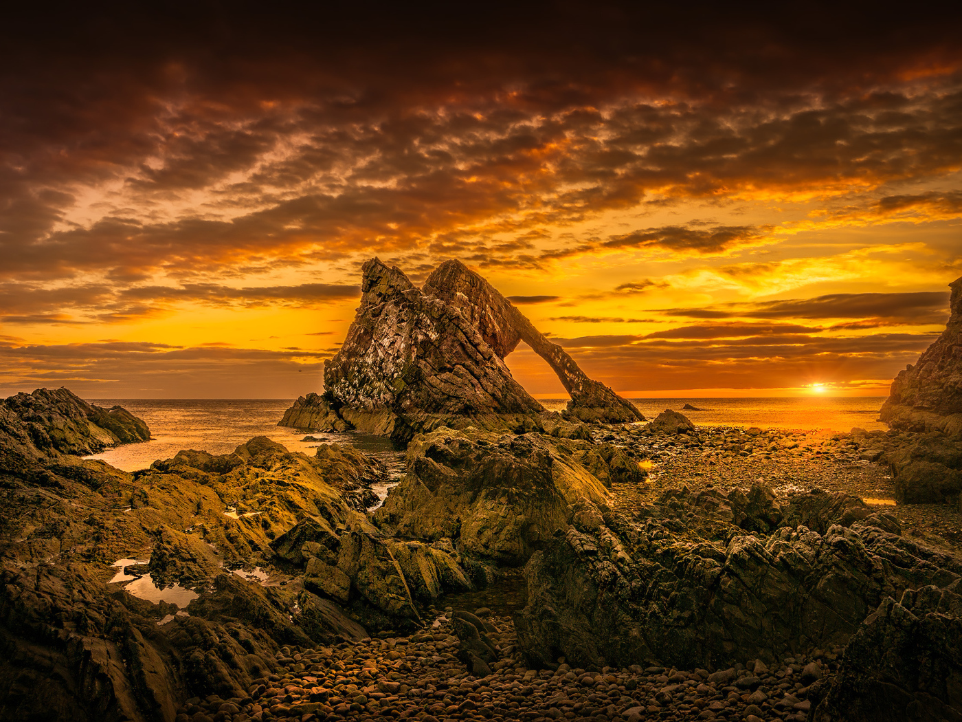 Скала в море на закате солнца под облачным небом