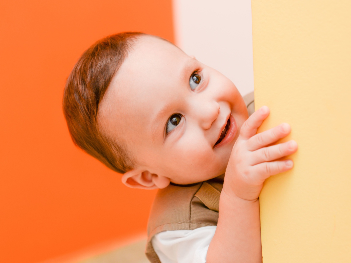 Маленький любопытный мальчик выглядывает из-за стены