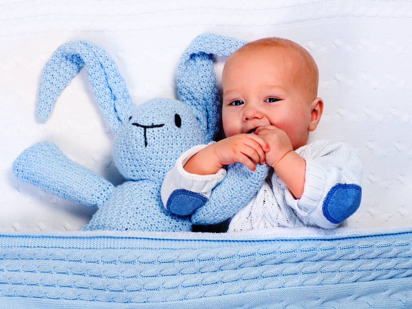 Маленький грудной ребенок грызет мягкую игрушку 