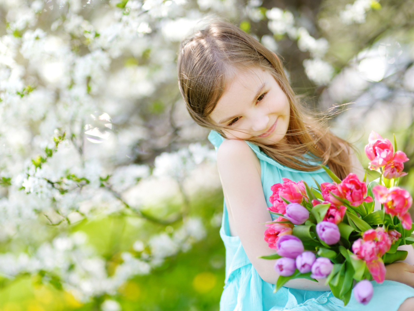 Красивая маленькая девочка с букетом тюльпанов весной