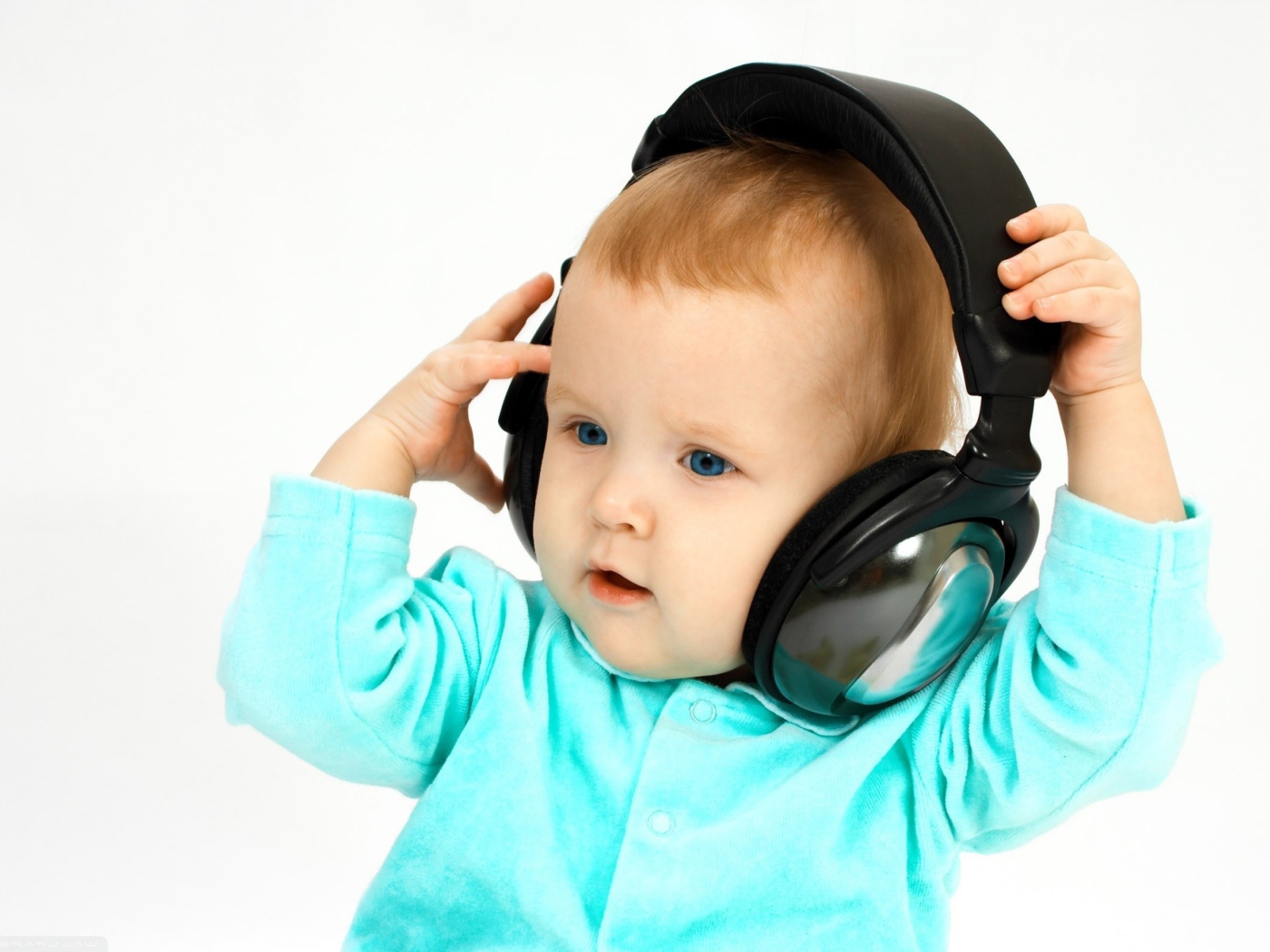 Голубоглазый мальчик в больших наушниках на белом фоне