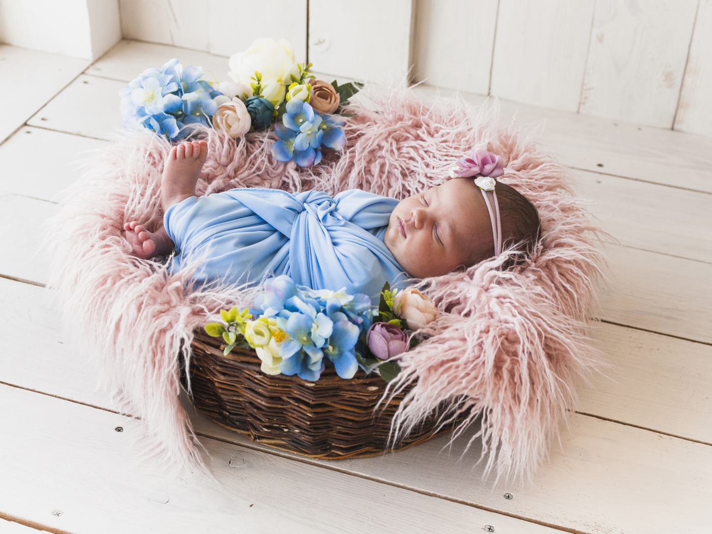 Маленький грудной ребенок спит в плетеной корзине 