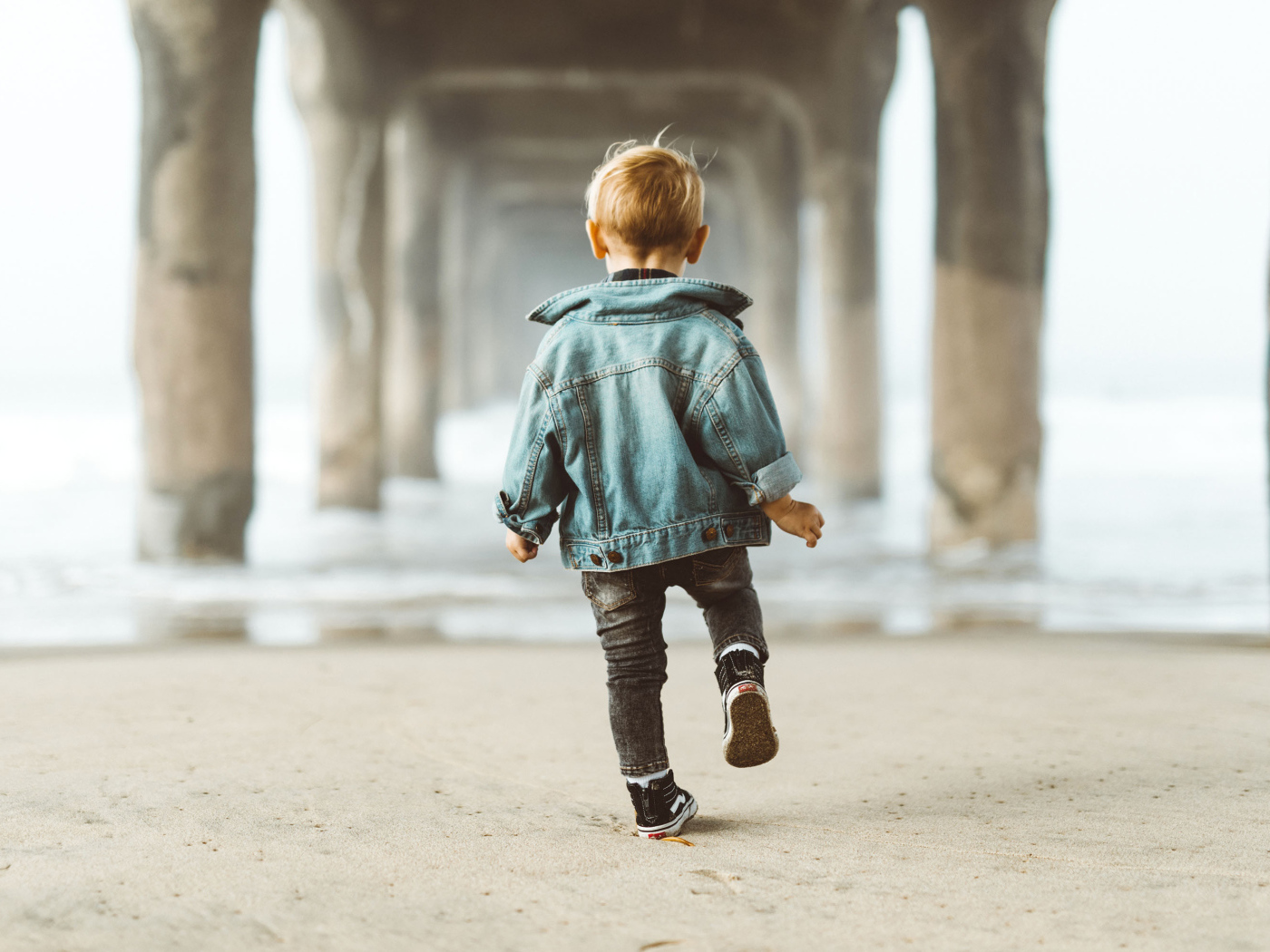 Маленький мальчик в джинсовой куртке спиной