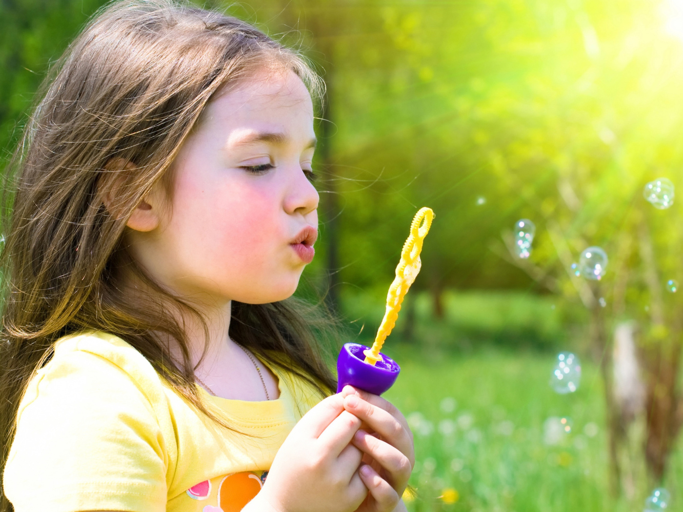 Маленькая девочка пускает мыльные пузыри