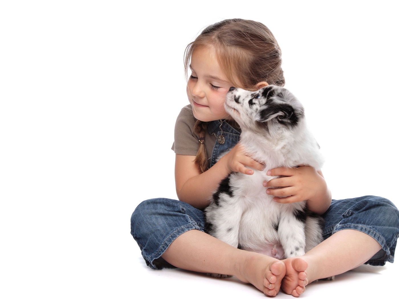 Маленькая девочка обнимает щенка на белом фоне