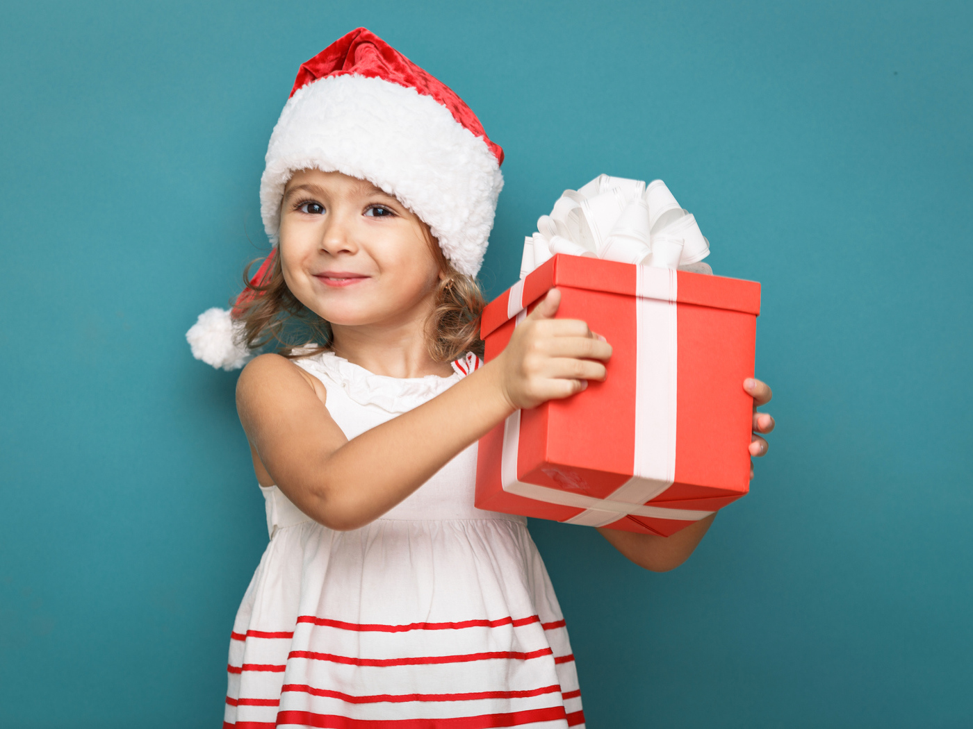 Маленькая девочка в новогоднем костюме с подарком на голубом фоне