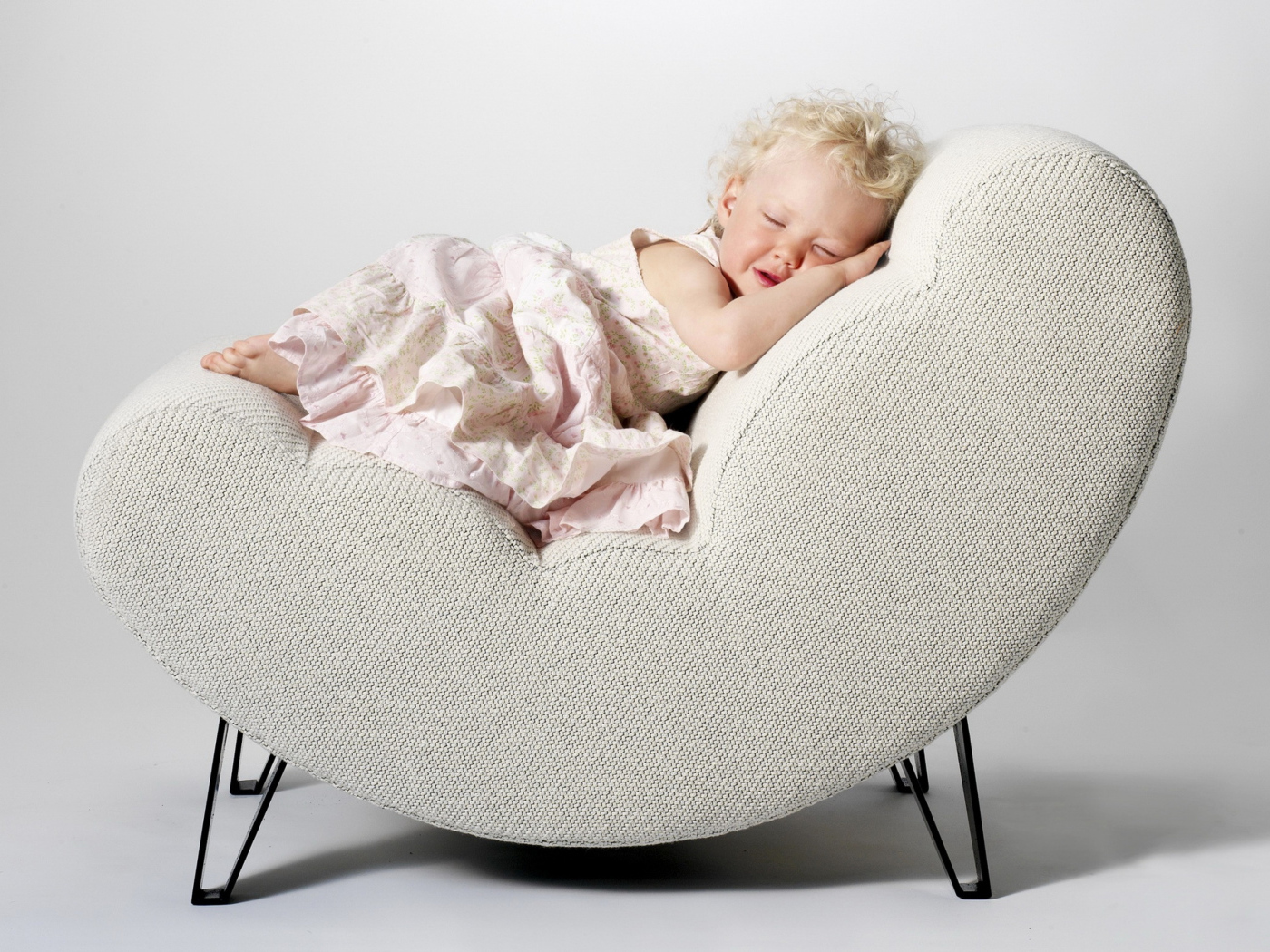 Маленькая девочка в розовом платье спит в кресле