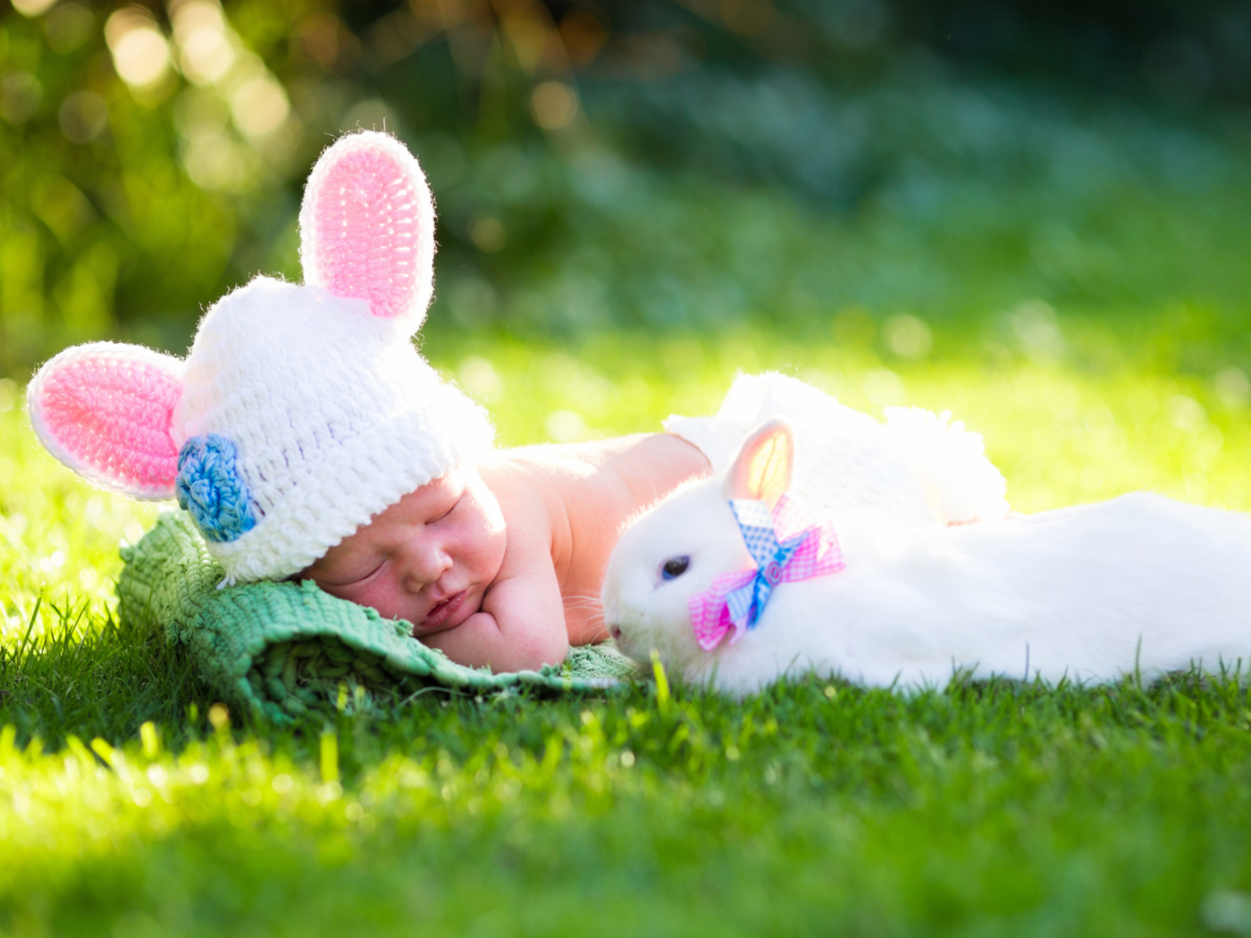 Маленький спящий грудной ребенок на зеленой траве с белым кроликом