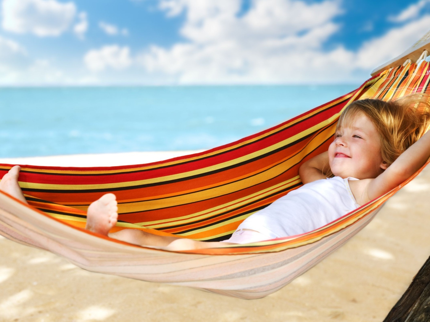 Маленькая улыбающаяся девочка в гамаке на пляже