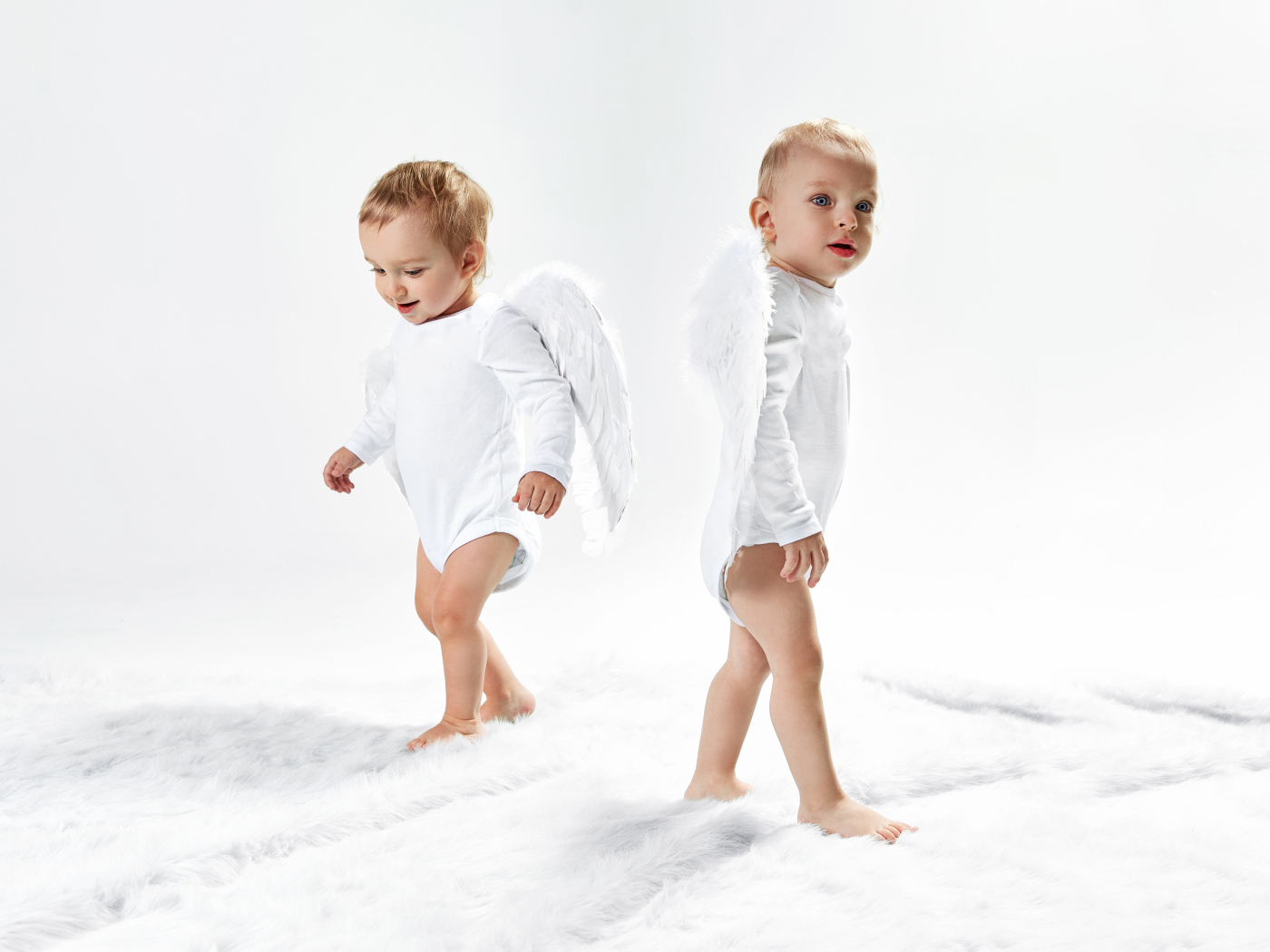 Два маленьких мальчика в костюмах ангела на белом фоне